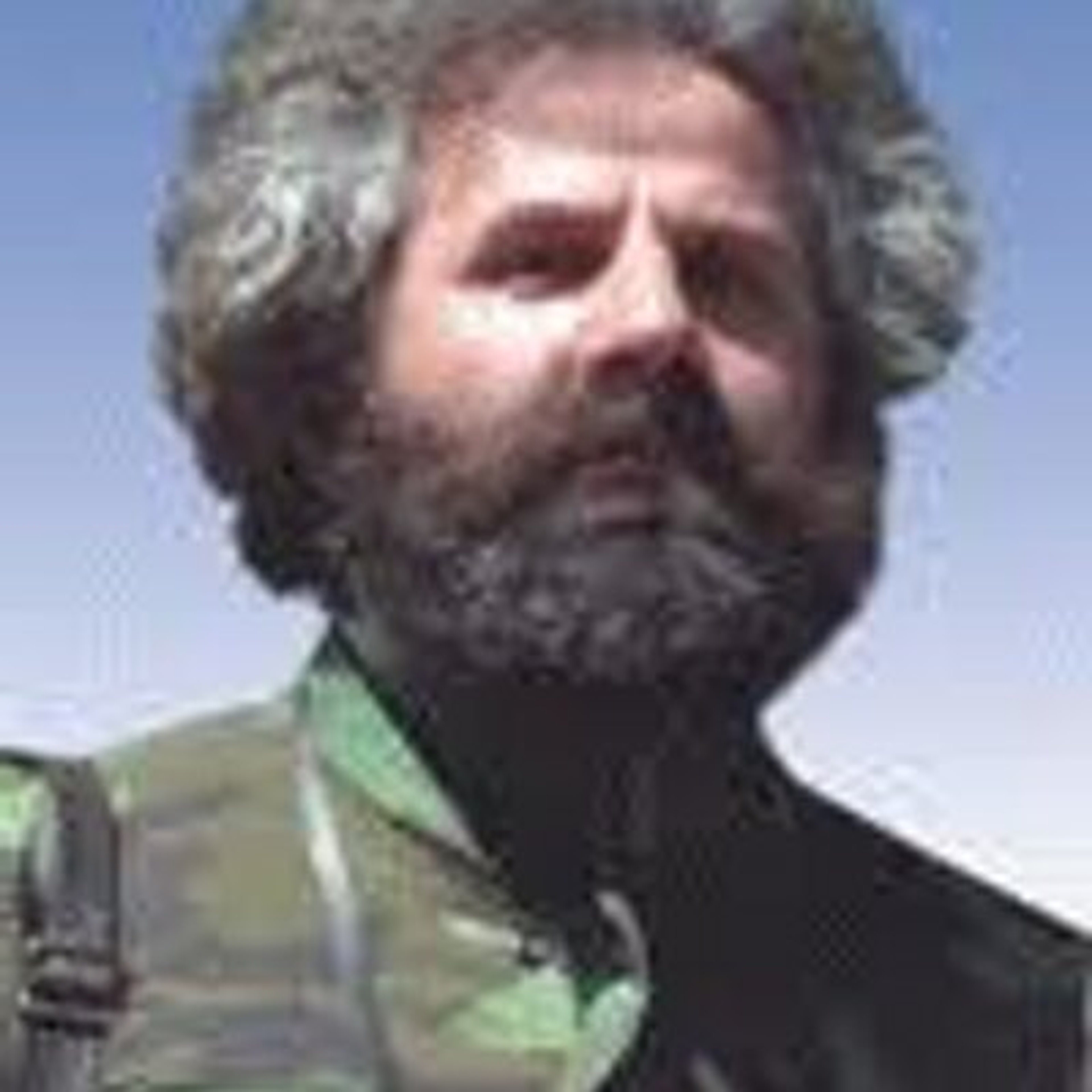 A middle-aged man with a long gray beard wearing a green military jacket