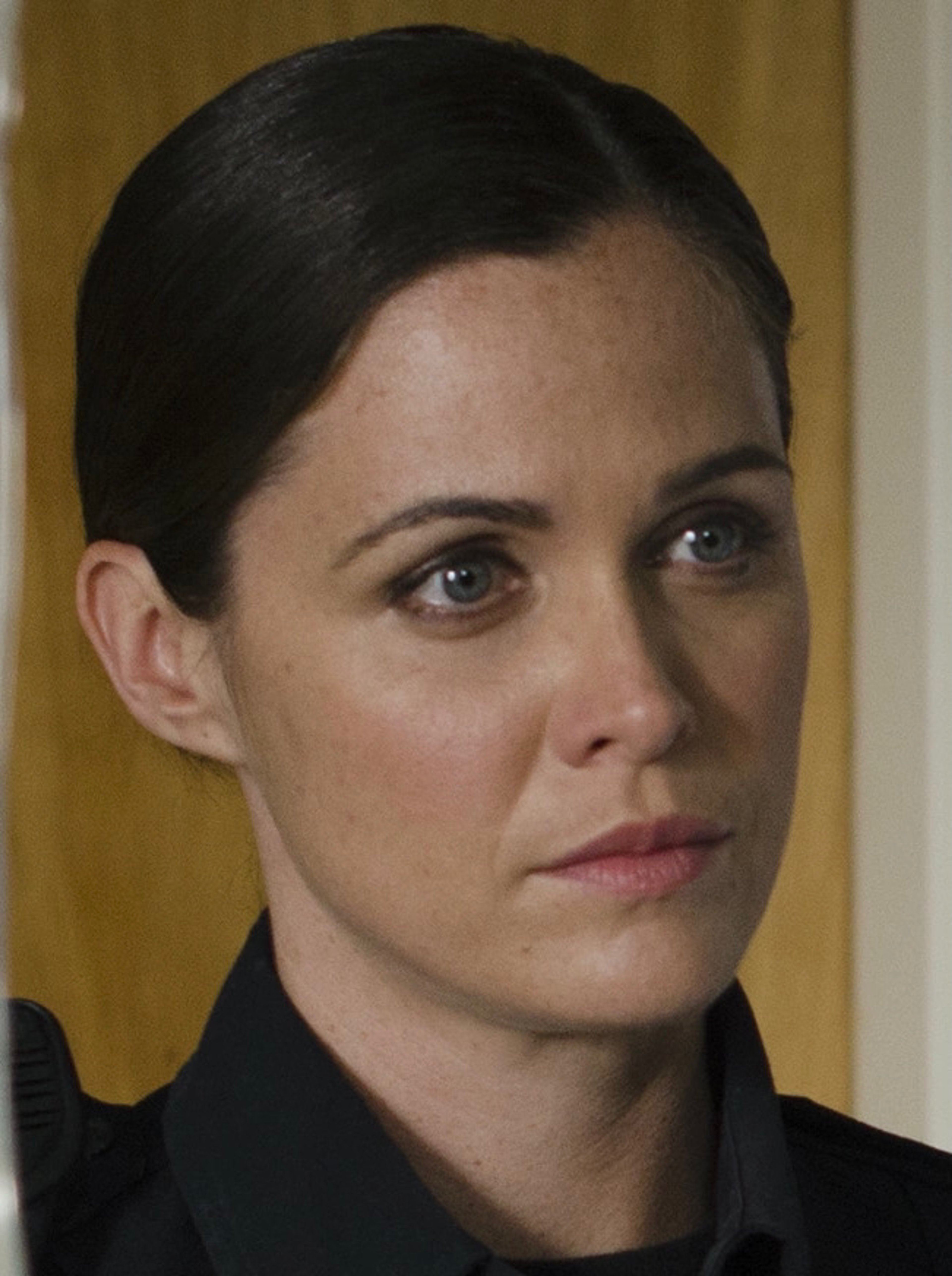 A woman with dark hair and a stern expression