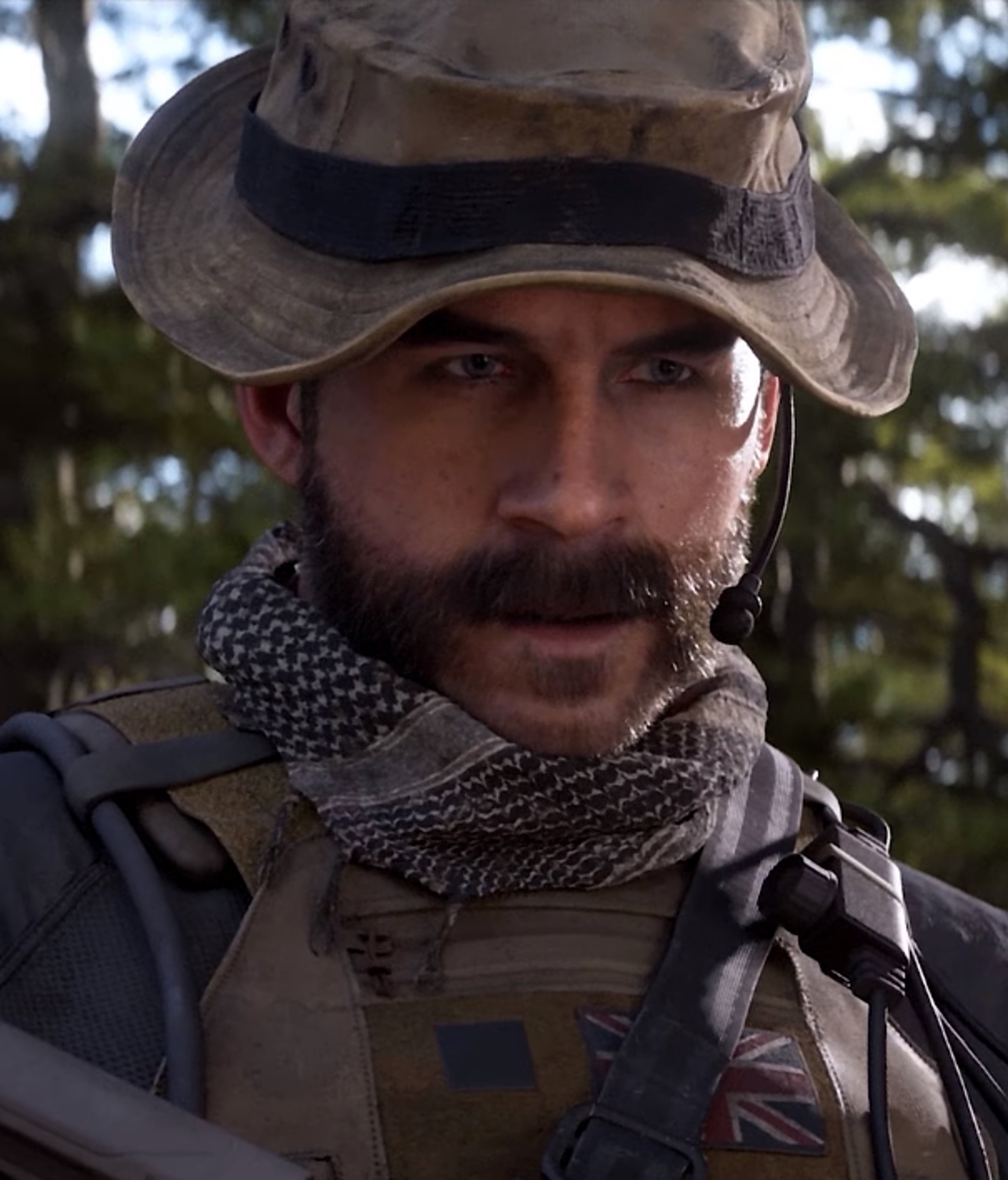 A grizzled, bearded military man in camouflage clothing with a serious expression