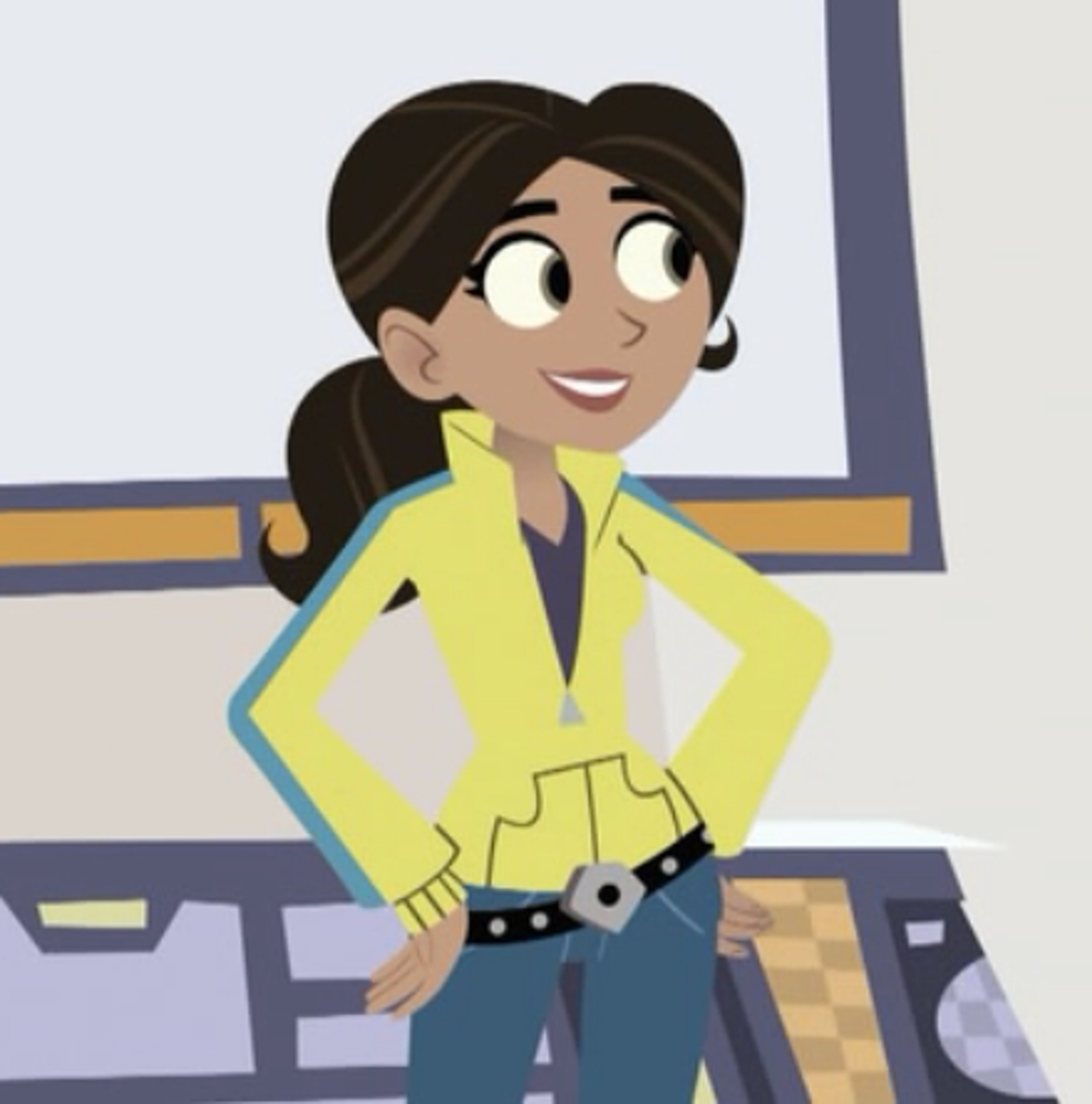 A young woman with dark hair in a ponytail, wearing a yellow jacket and blue jeans, standing in a classroom or laboratory setting.