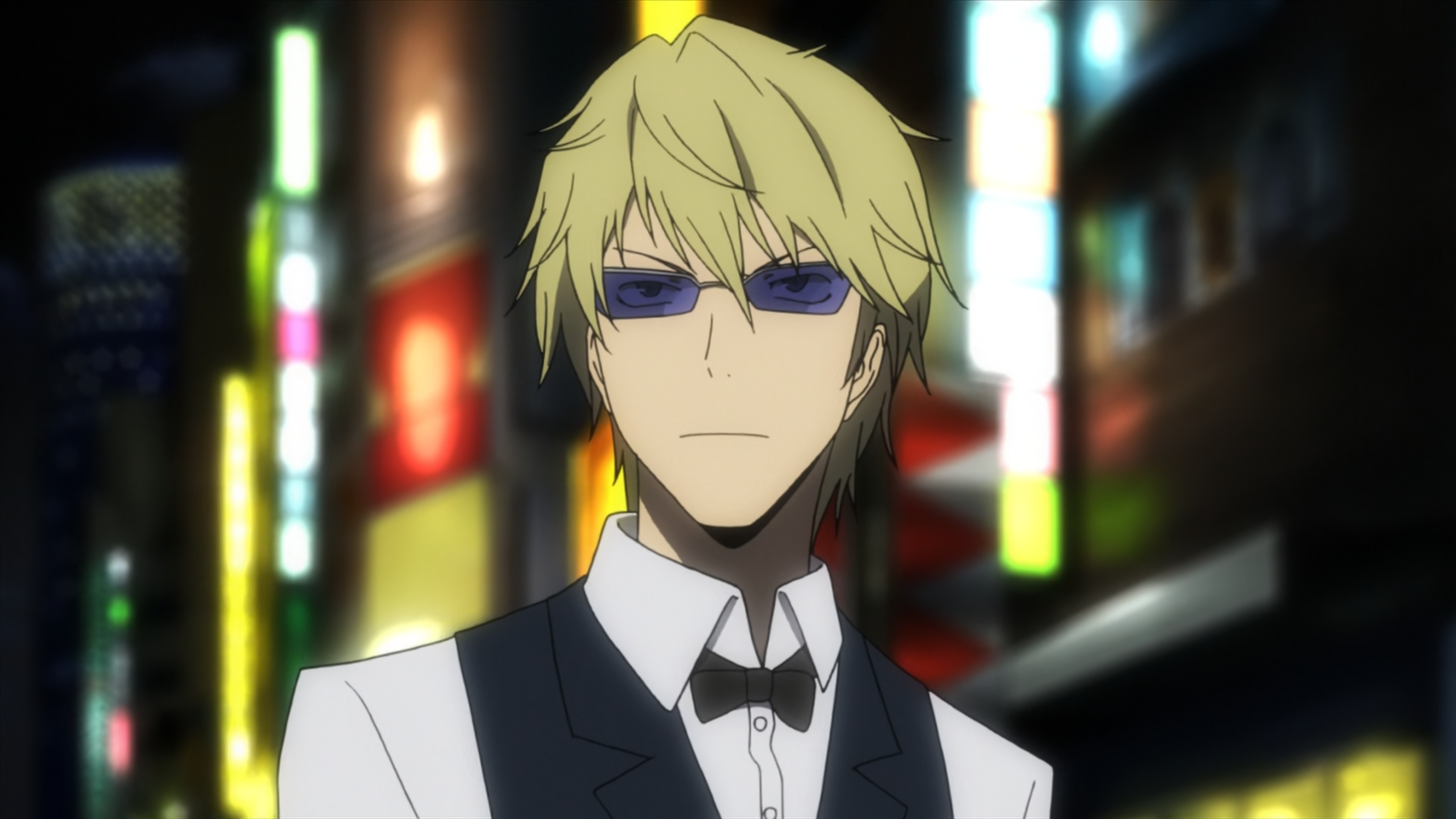 A blond-haired man in a bartender uniform with a serious expression