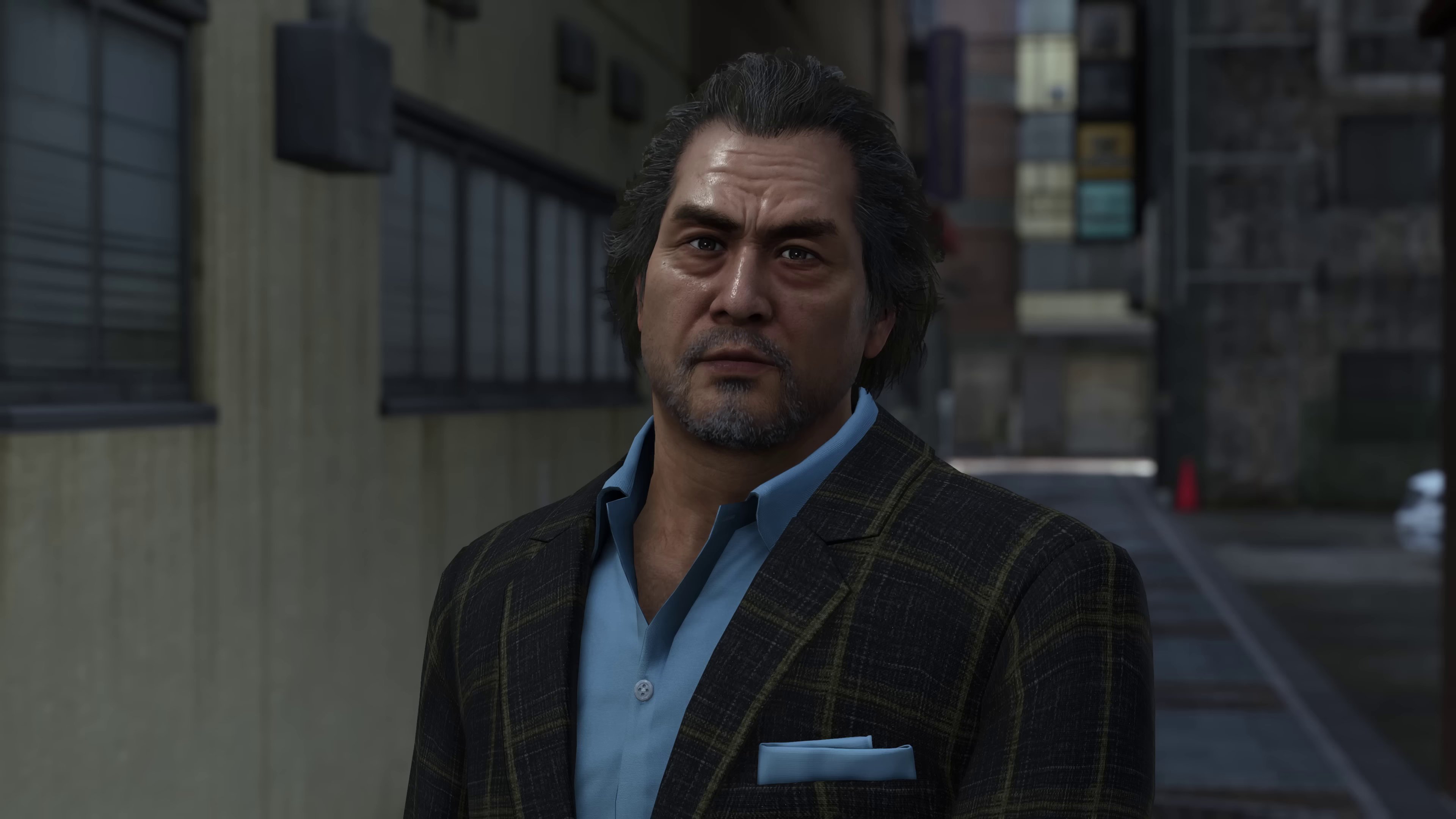 A middle-aged man with a muscular build, graying hair, and a distinctive blue bomber jacket.