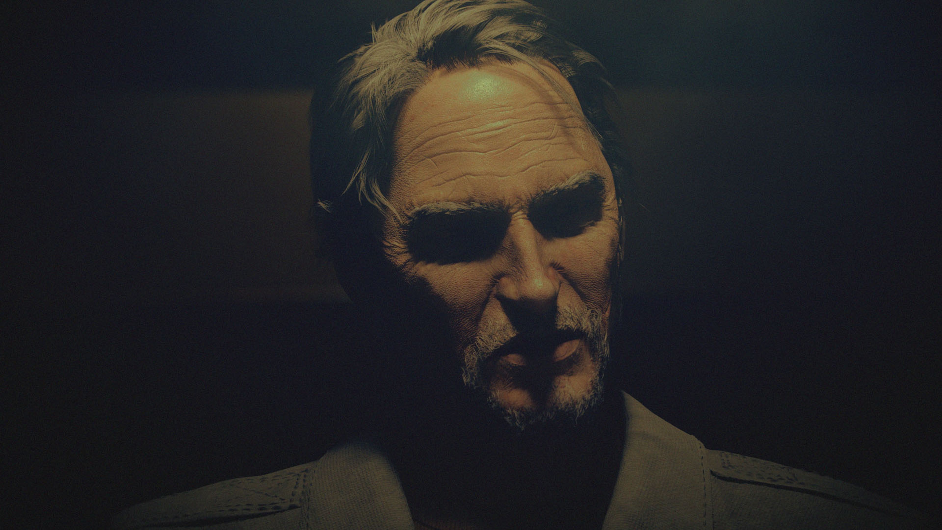 A middle-aged man in a dark suit with a serious expression