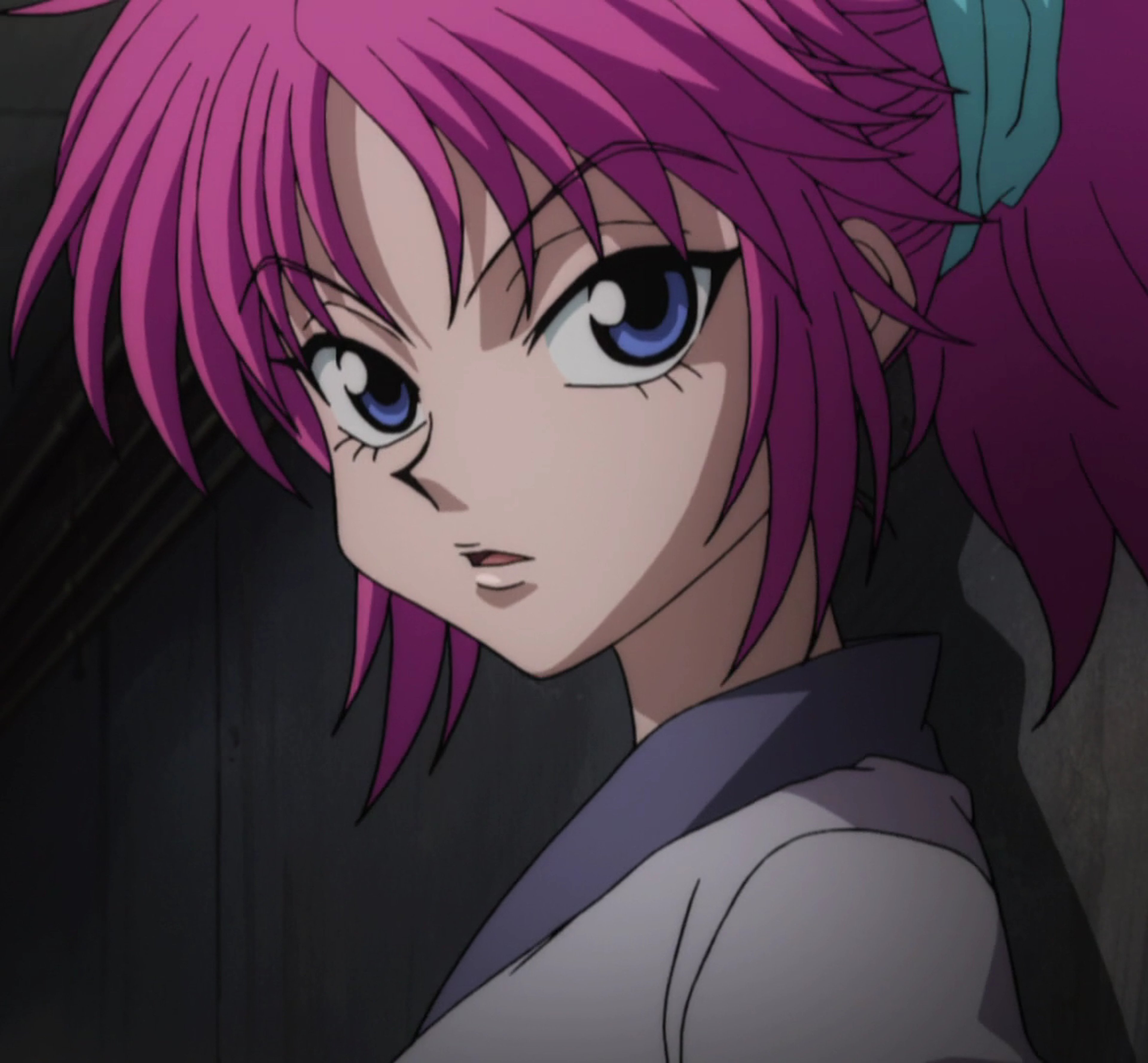 A young woman with pink hair and a serious expression