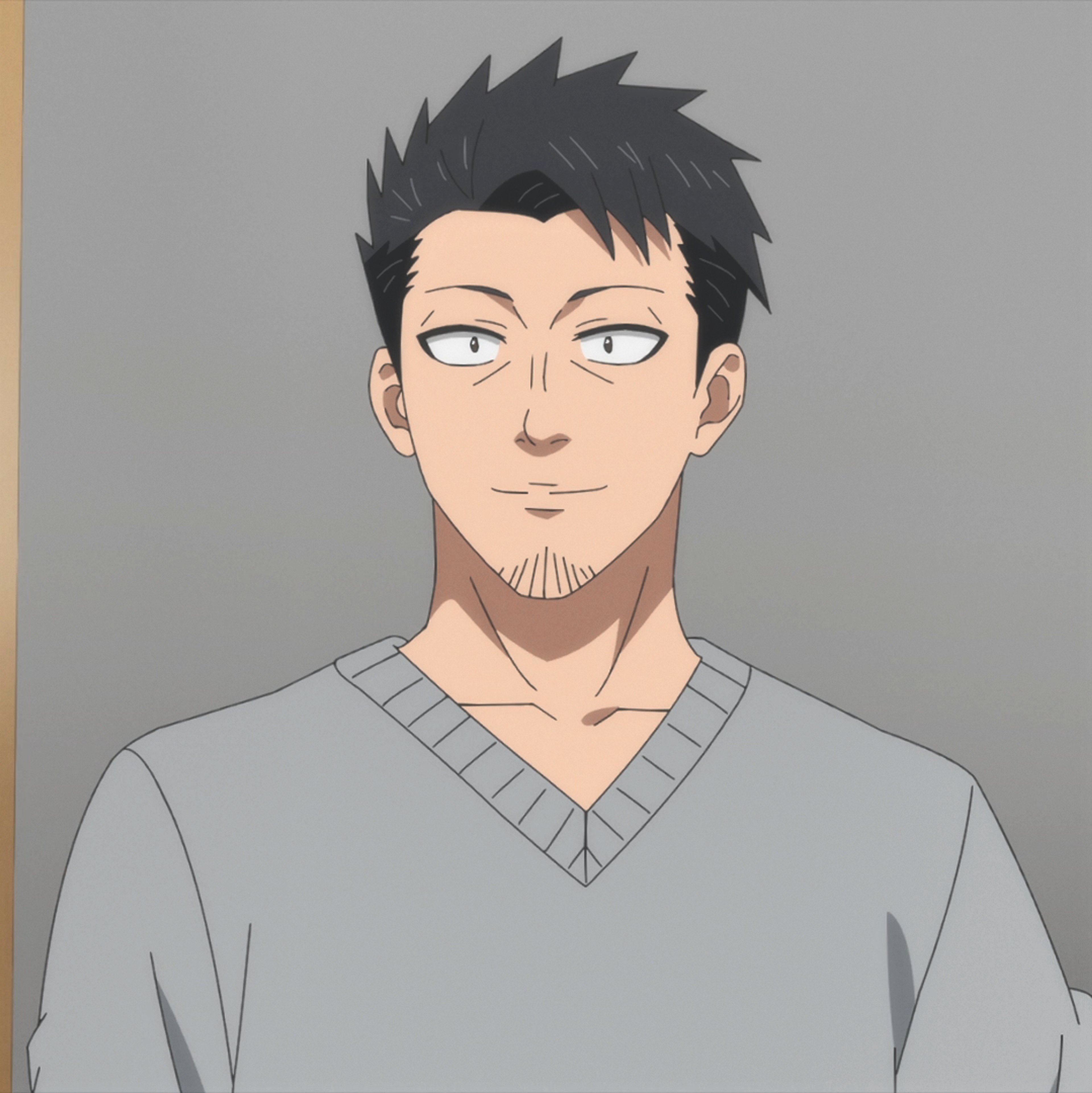 A middle-aged man with short black hair, blue eyes, and a muscular build wearing a gray sweater.