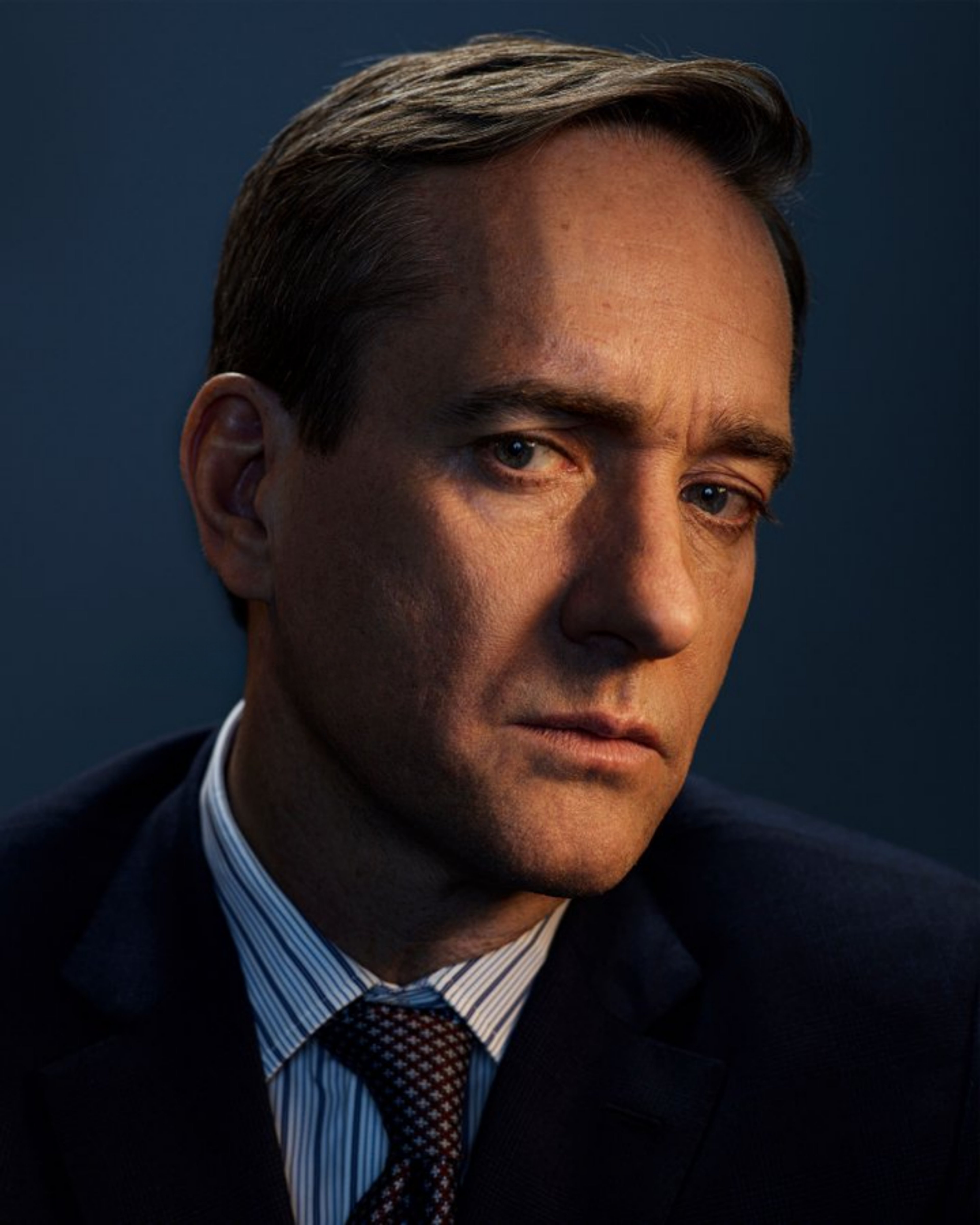 A well-dressed middle-aged man with a serious expression