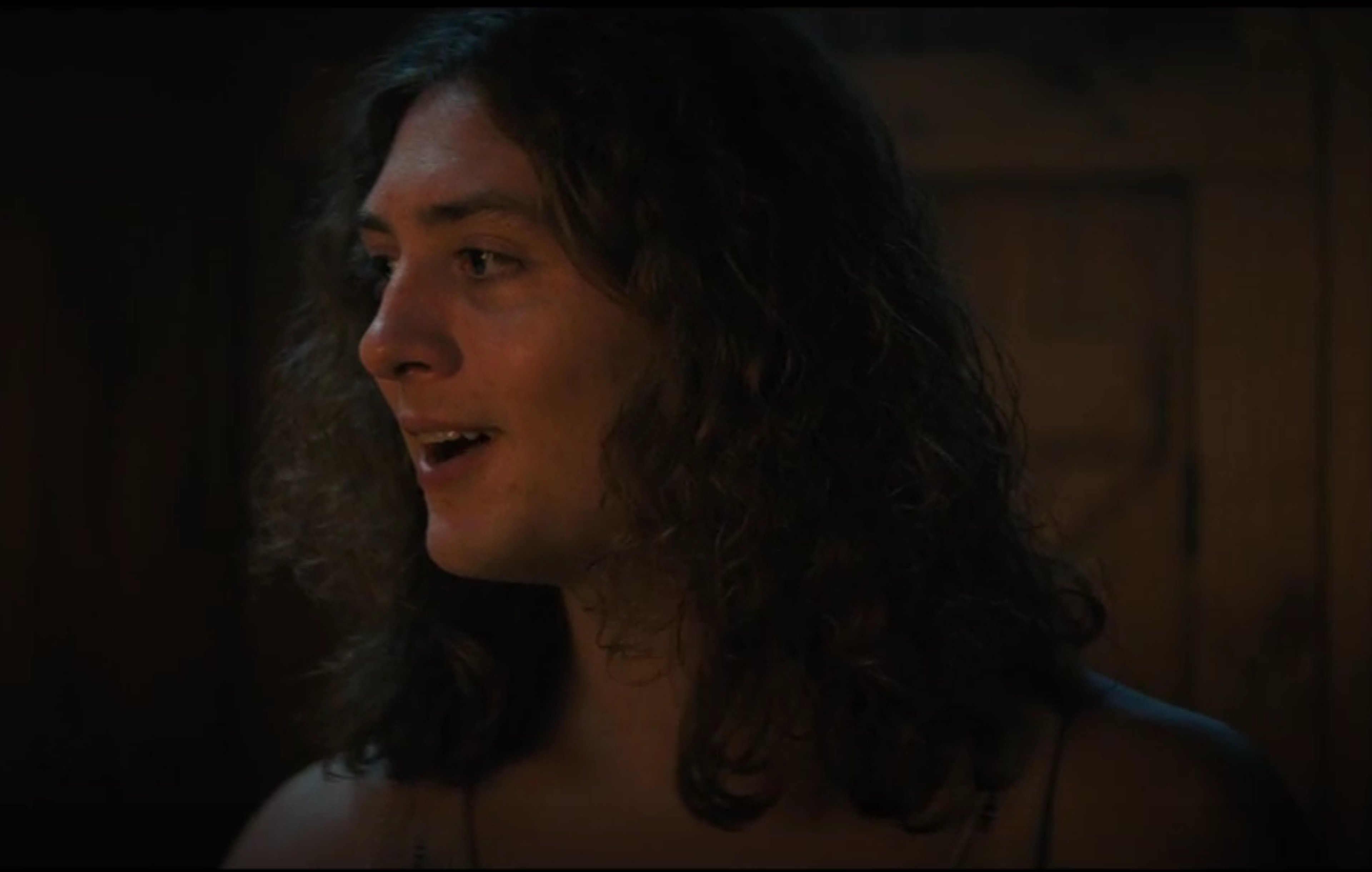 A young man with long, dark hair in a casual, rebellious pose