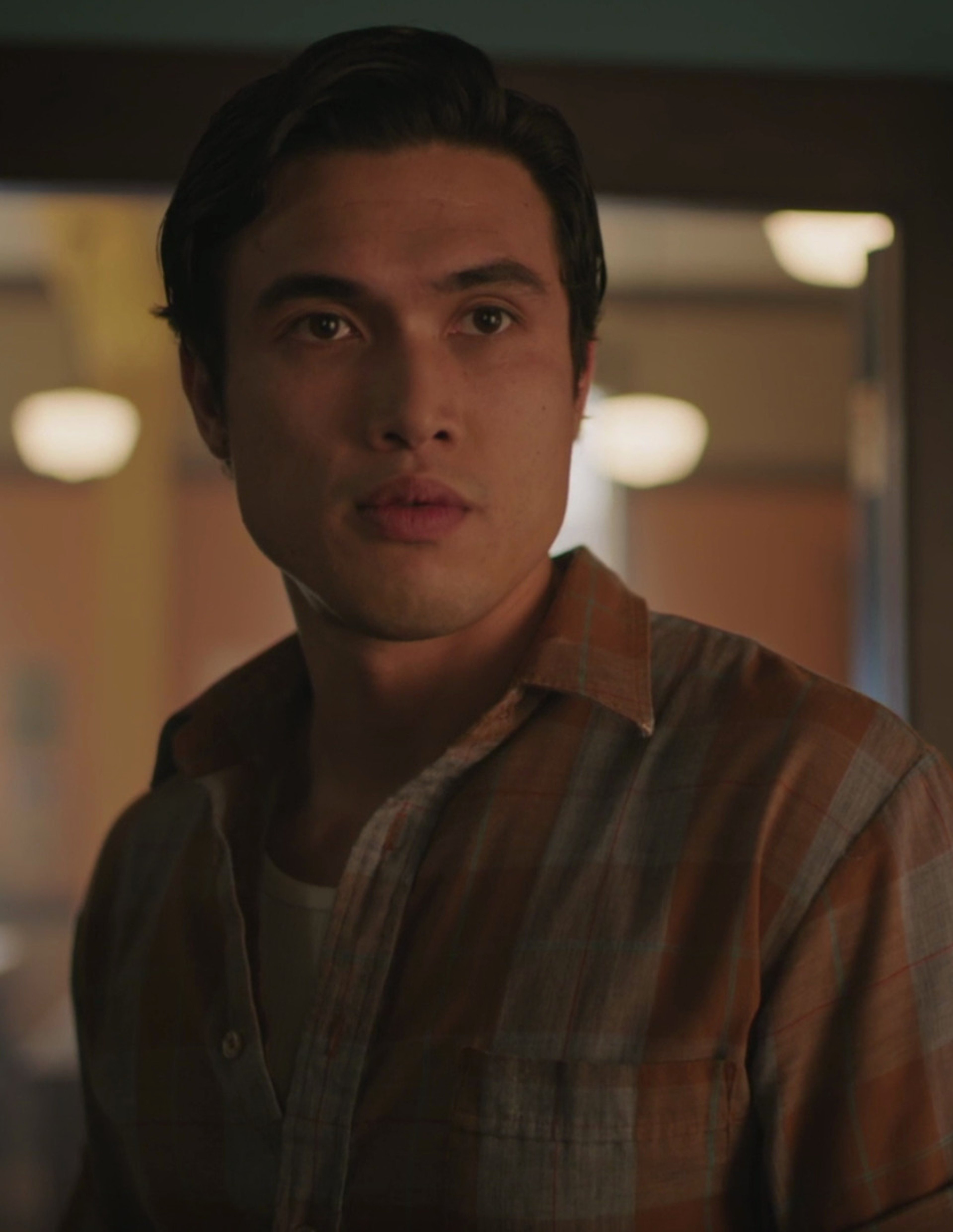 A young man with dark hair and a muscular build wearing a striped shirt