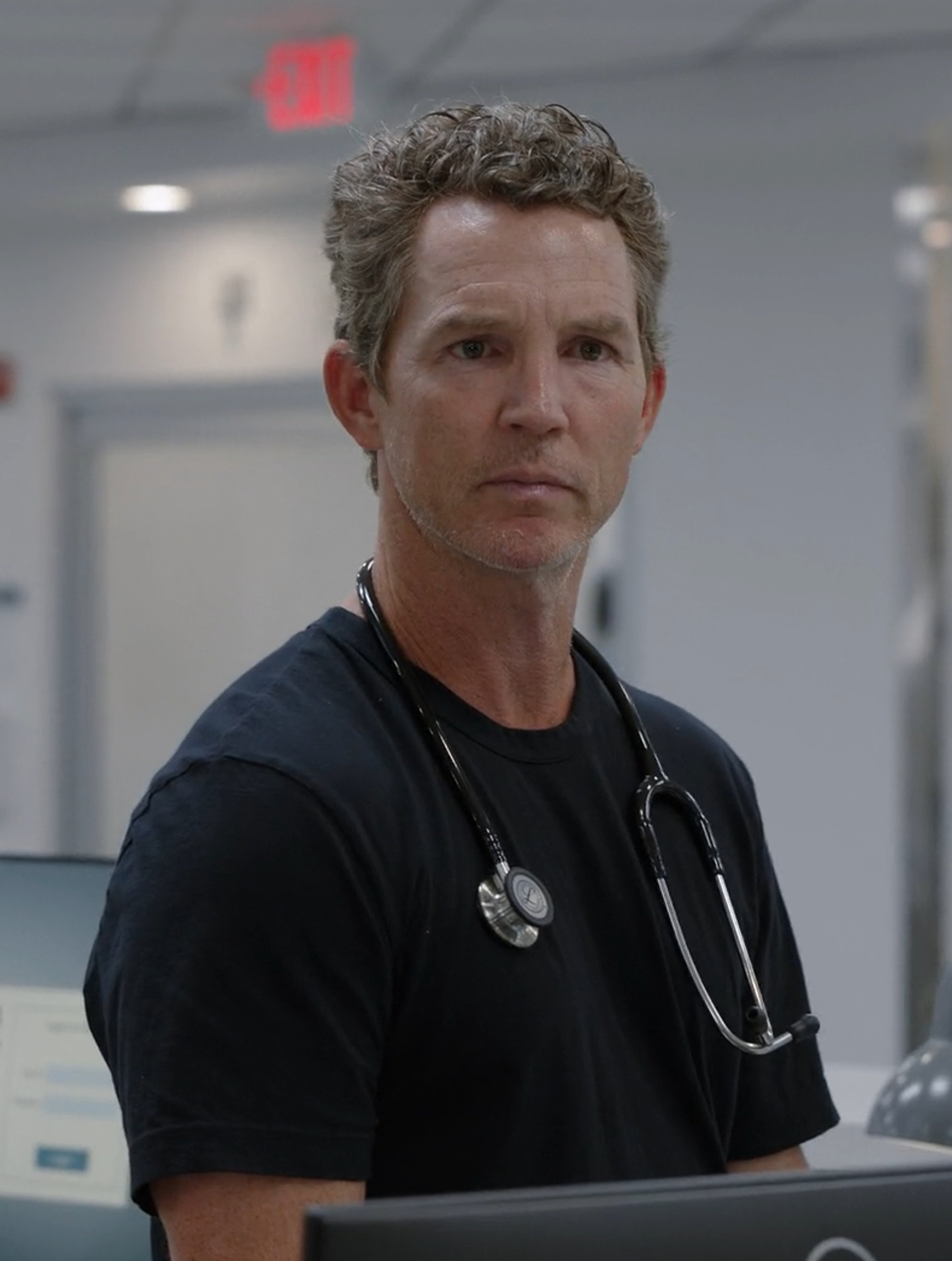 A middle-aged man in medical scrubs with a stethoscope