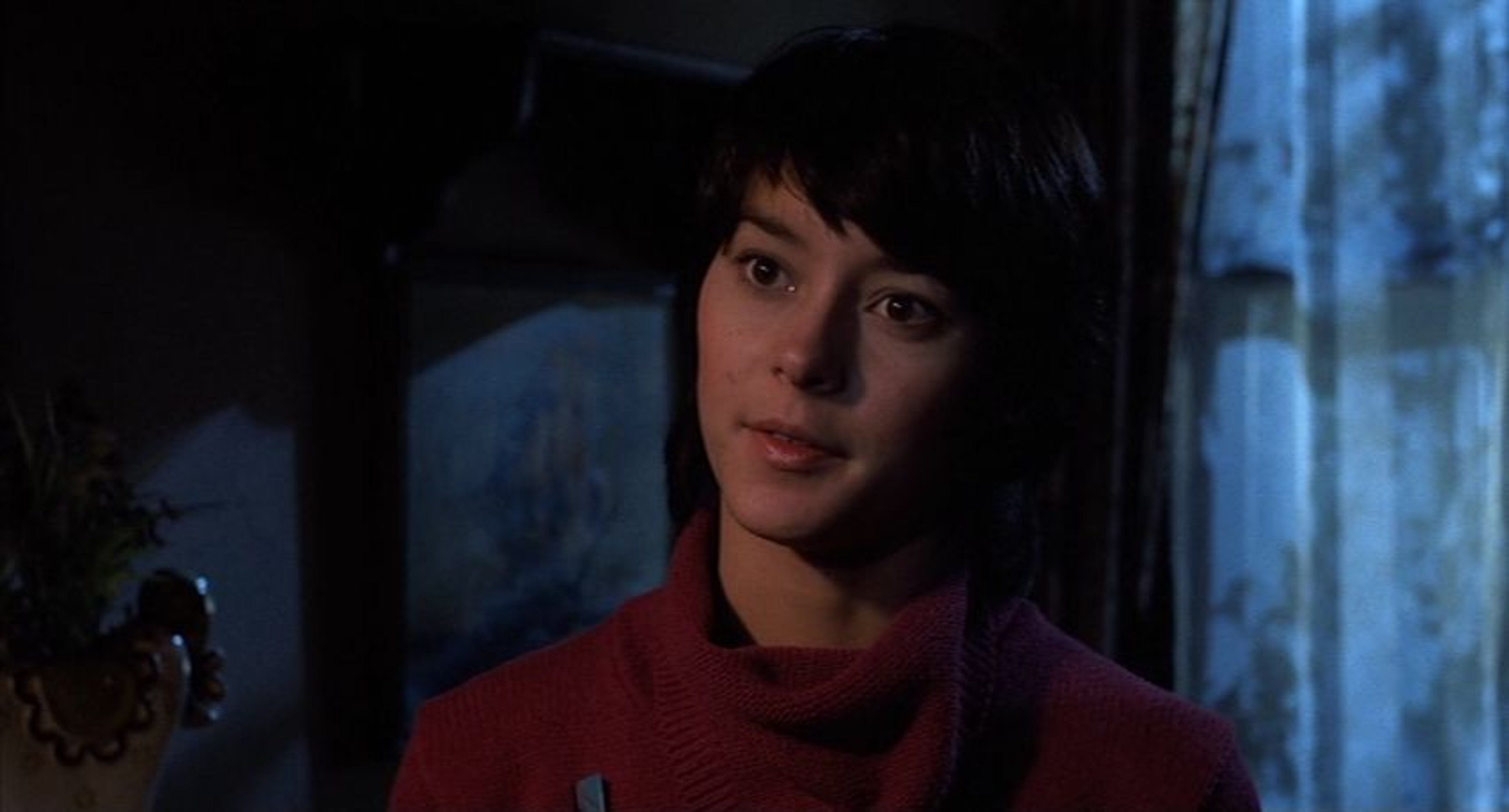 A young woman with dark hair and a pensive expression