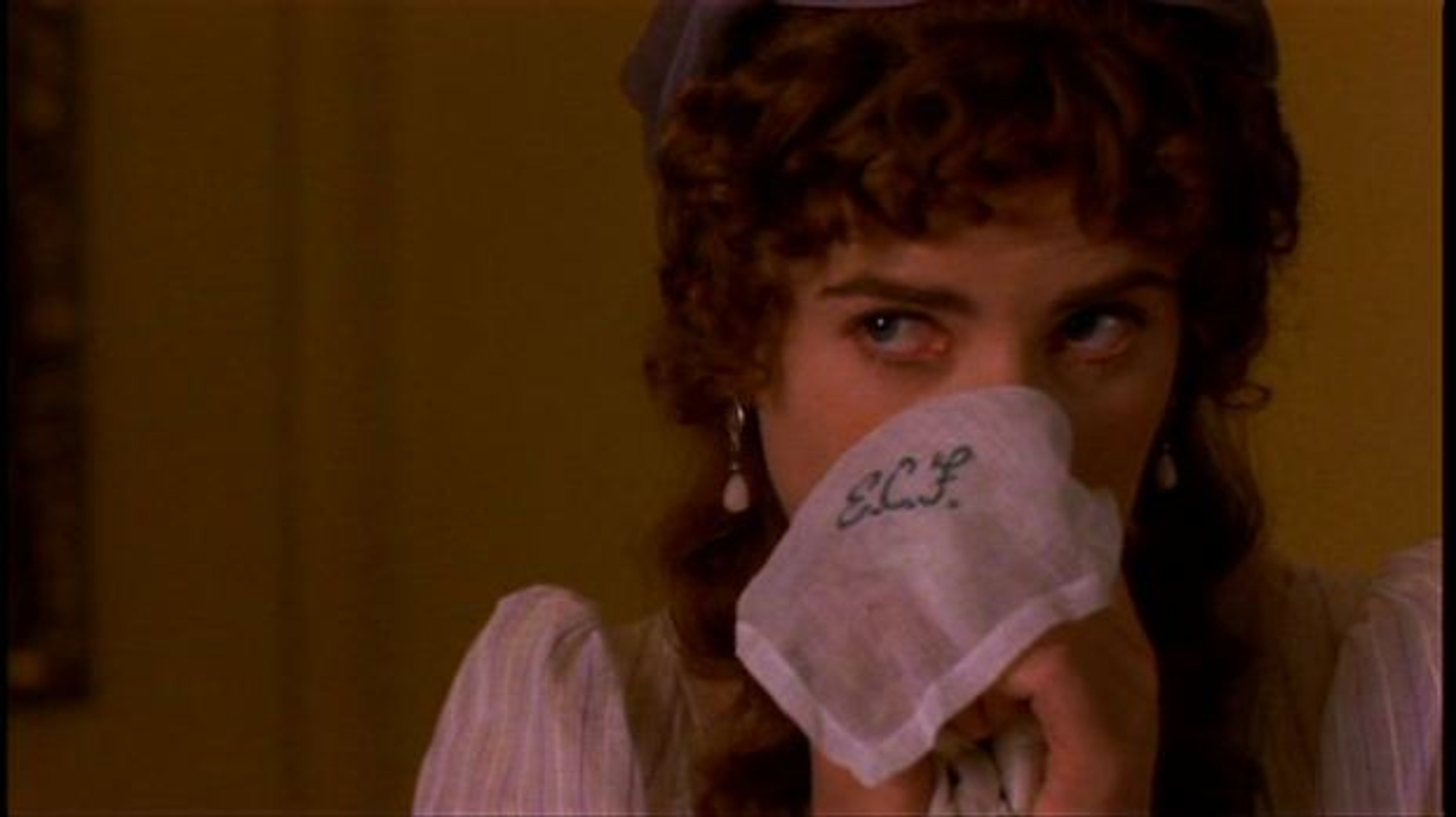 A young woman in a period dress covering her mouth with her hand