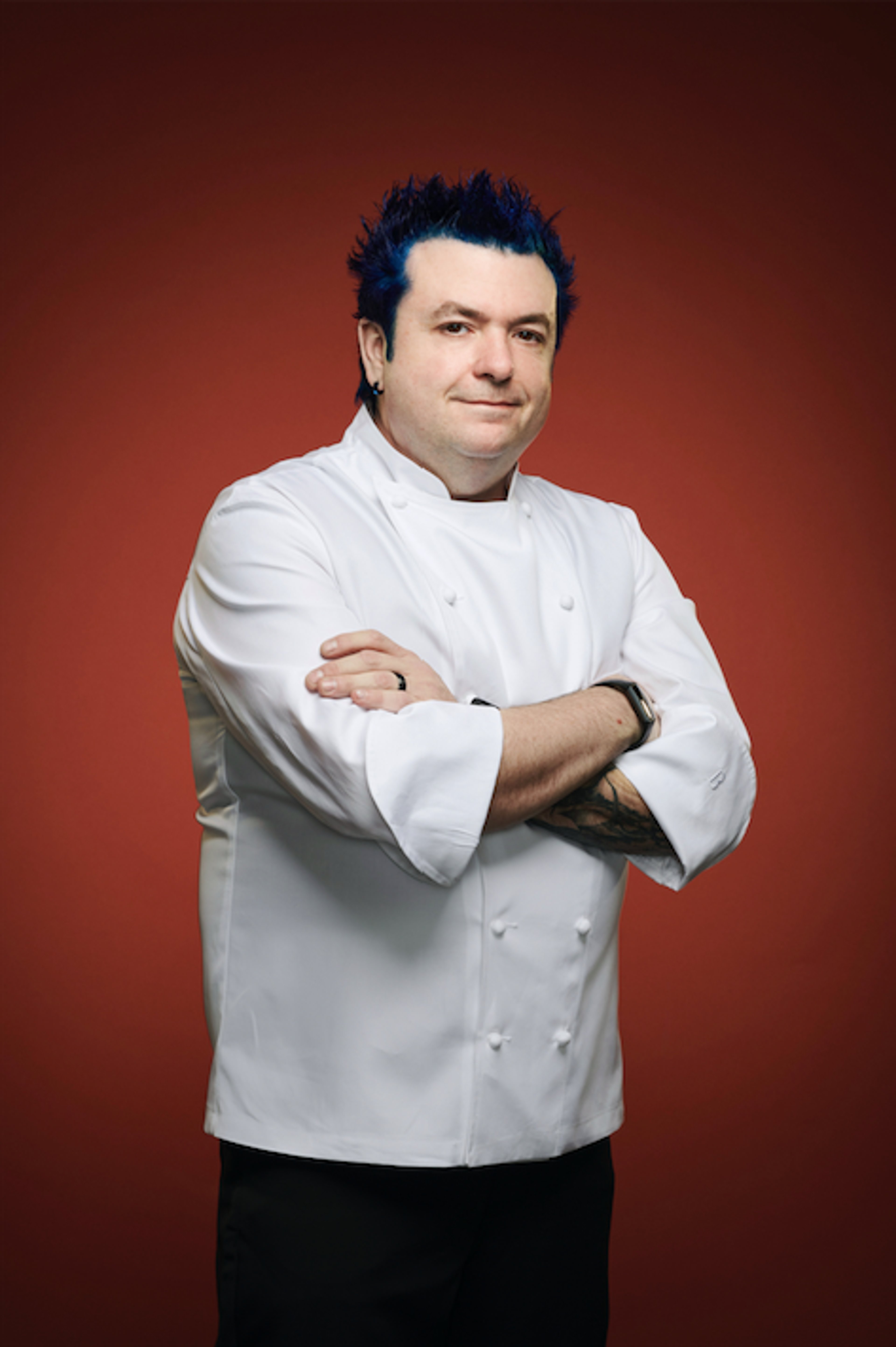 A middle-aged man with blue hair wearing a chef's uniform