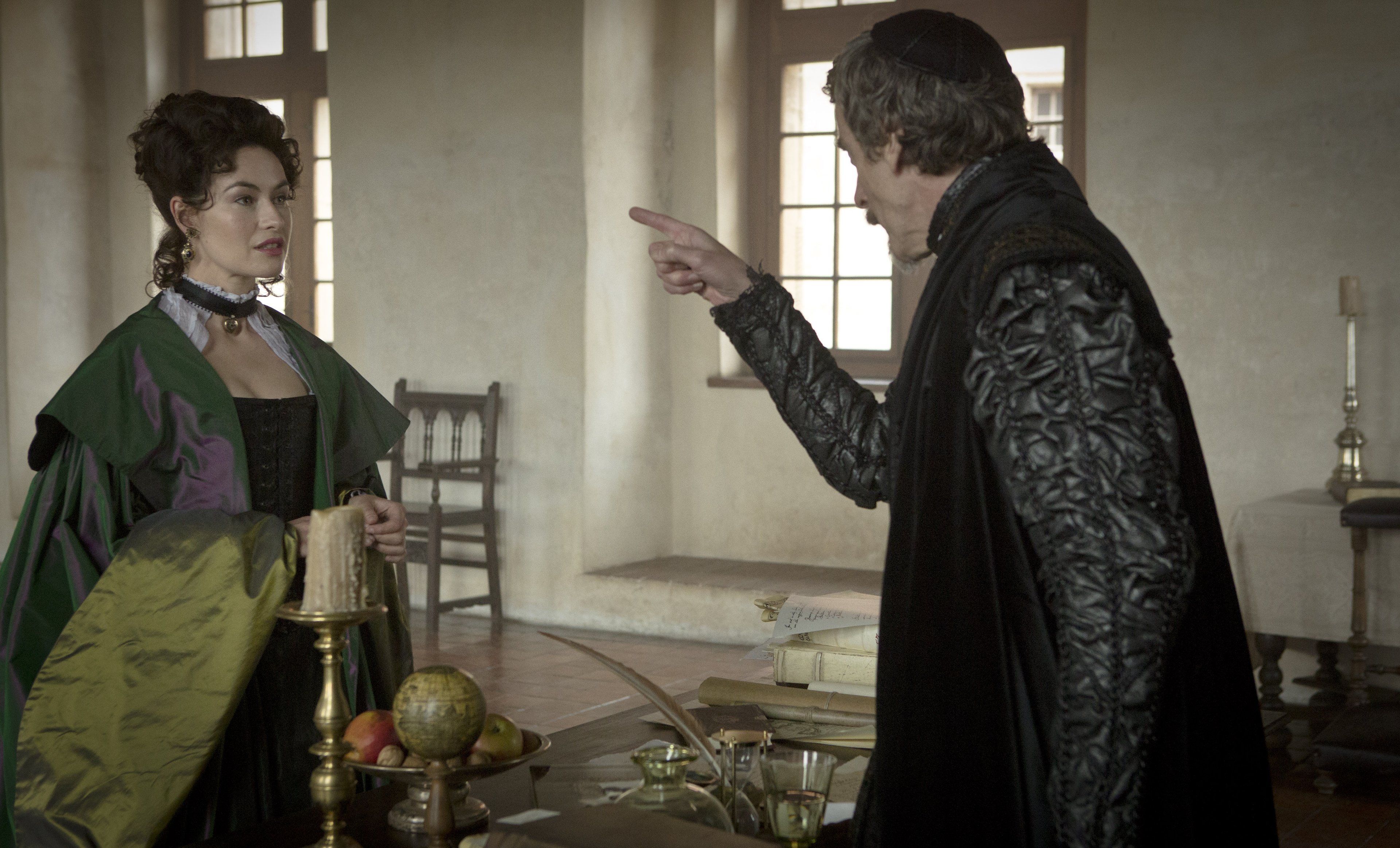A woman in a green dress and a man in a dark coat in a room