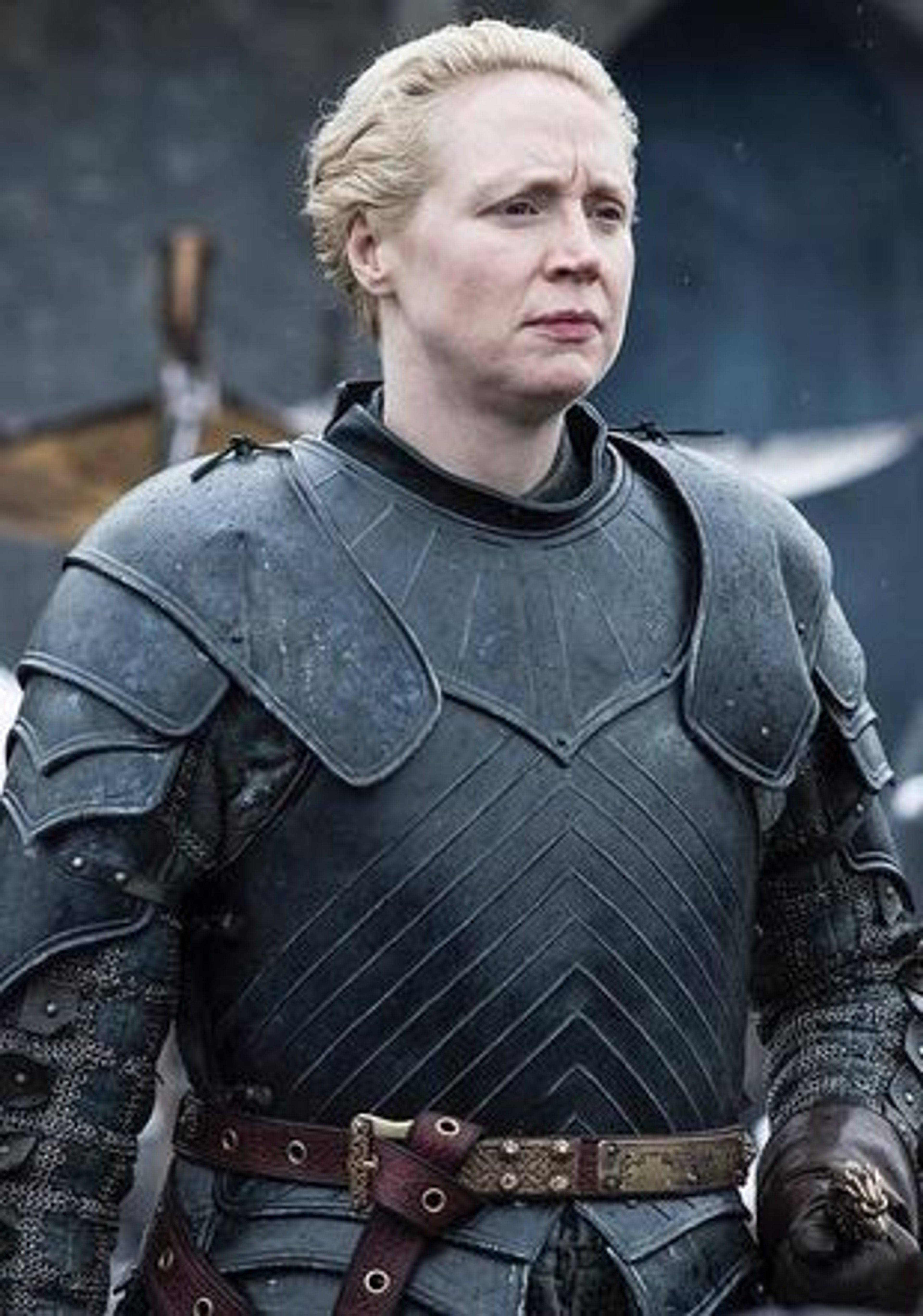 A woman in dark armor with a muscular build and short blonde hair