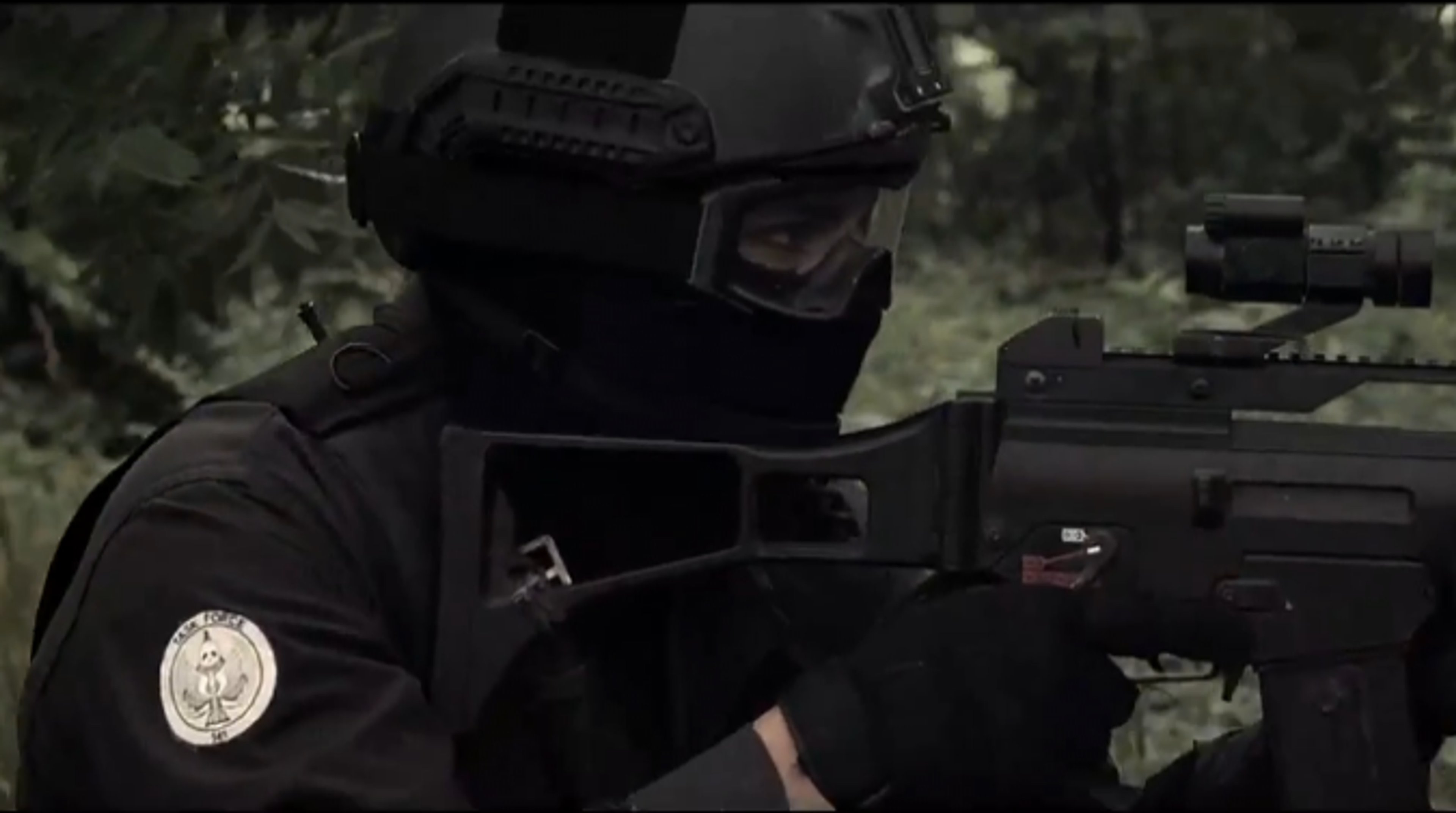 A man in tactical gear holding an assault rifle