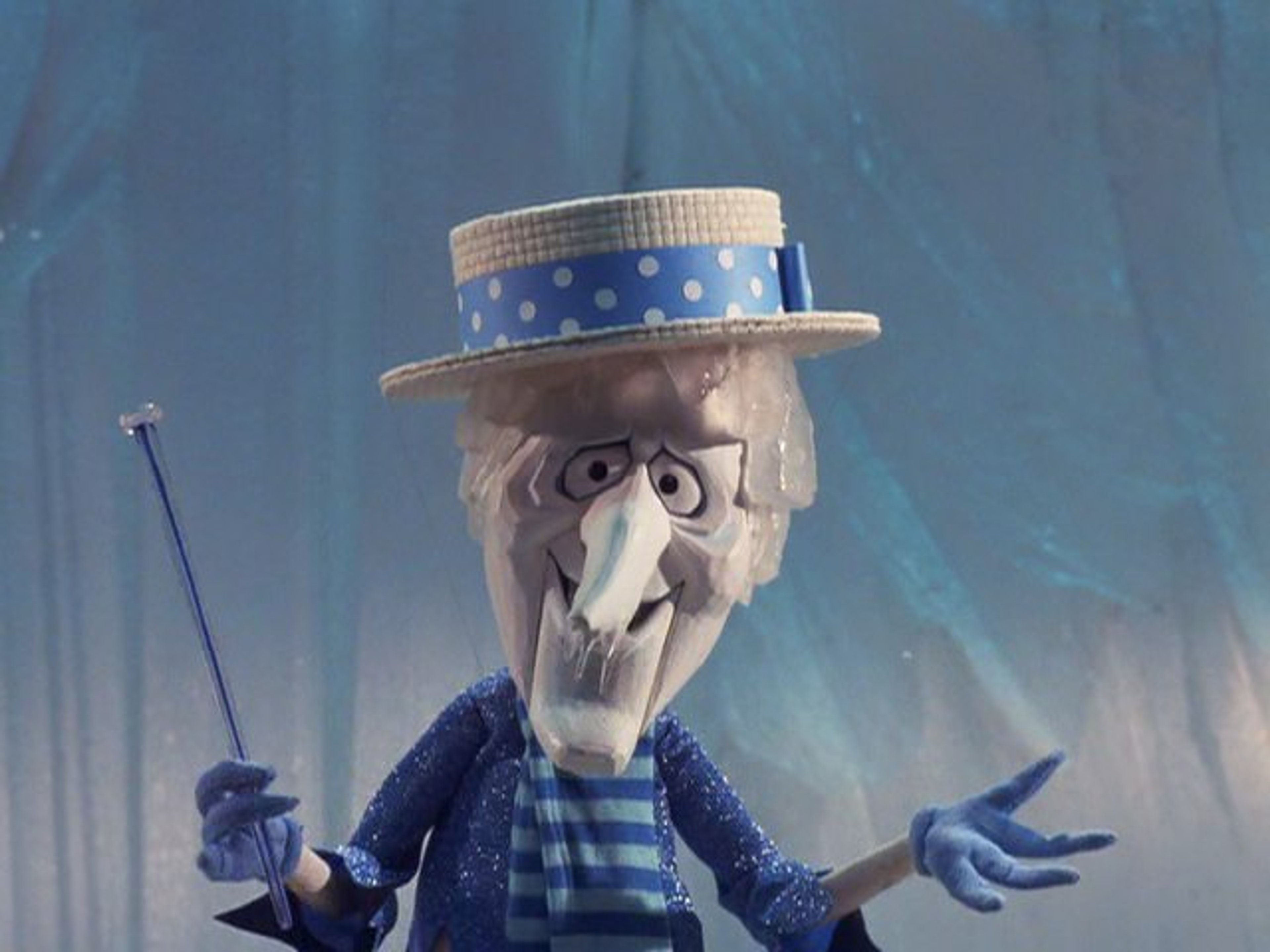 A detailed puppet or animatronic character with a large nose and polka dot hat, wearing a blue and white striped outfit and having a mischievous expression.