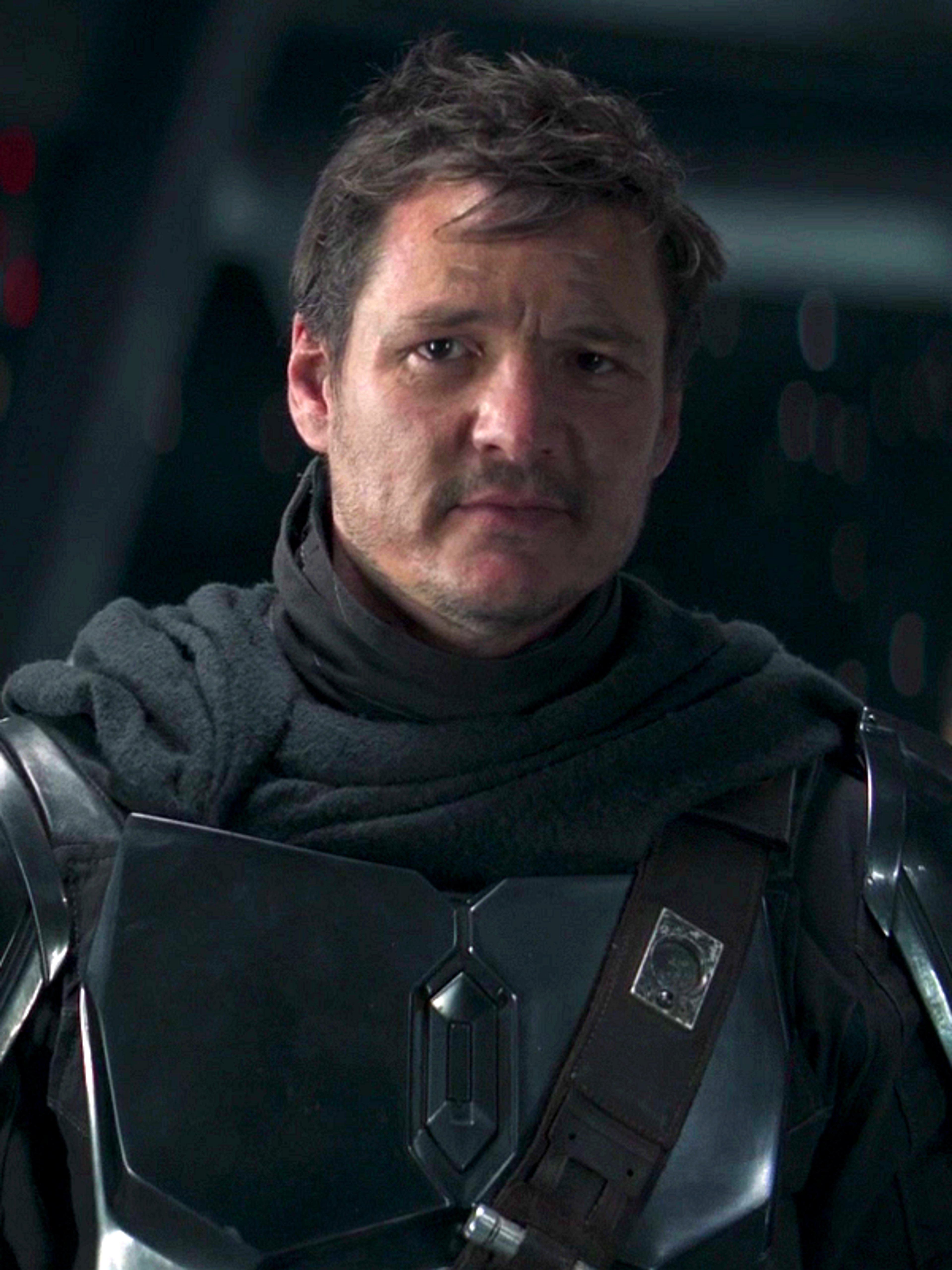 A man in dark gray armor with a serious expression