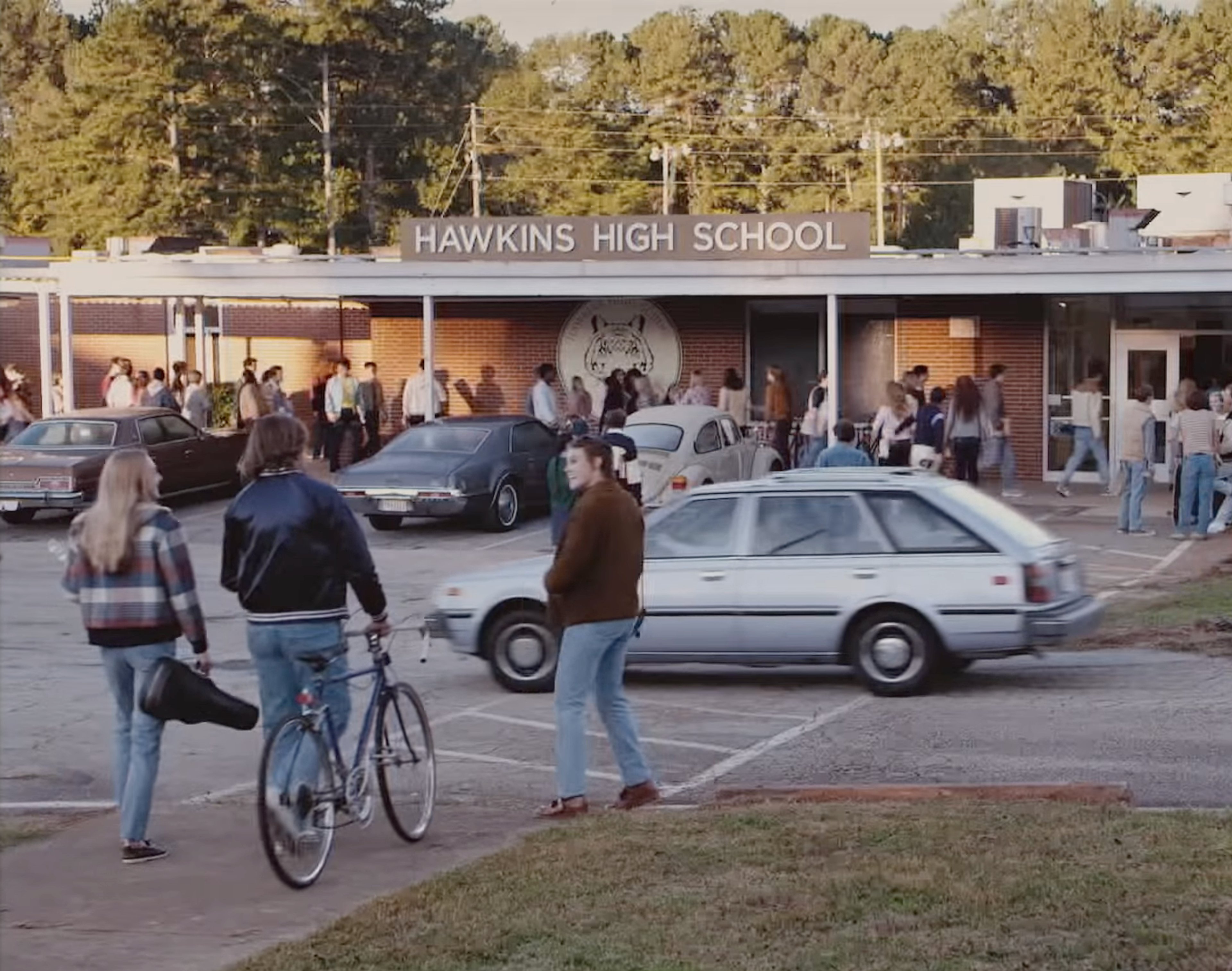 An image of Hawkins High School, a 1980s-style high school building with people outside