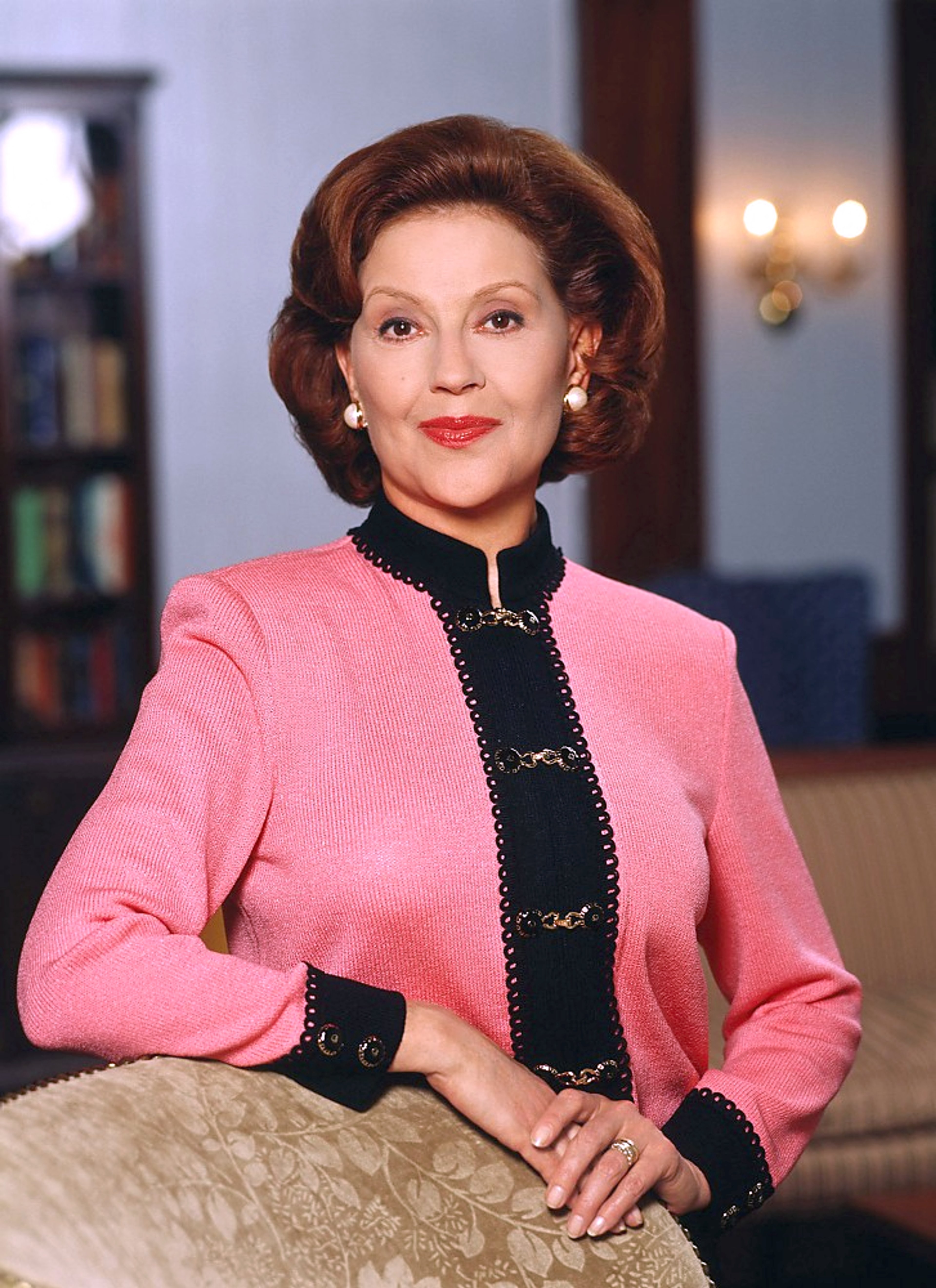 A well-dressed older woman with curled hair sitting in a room