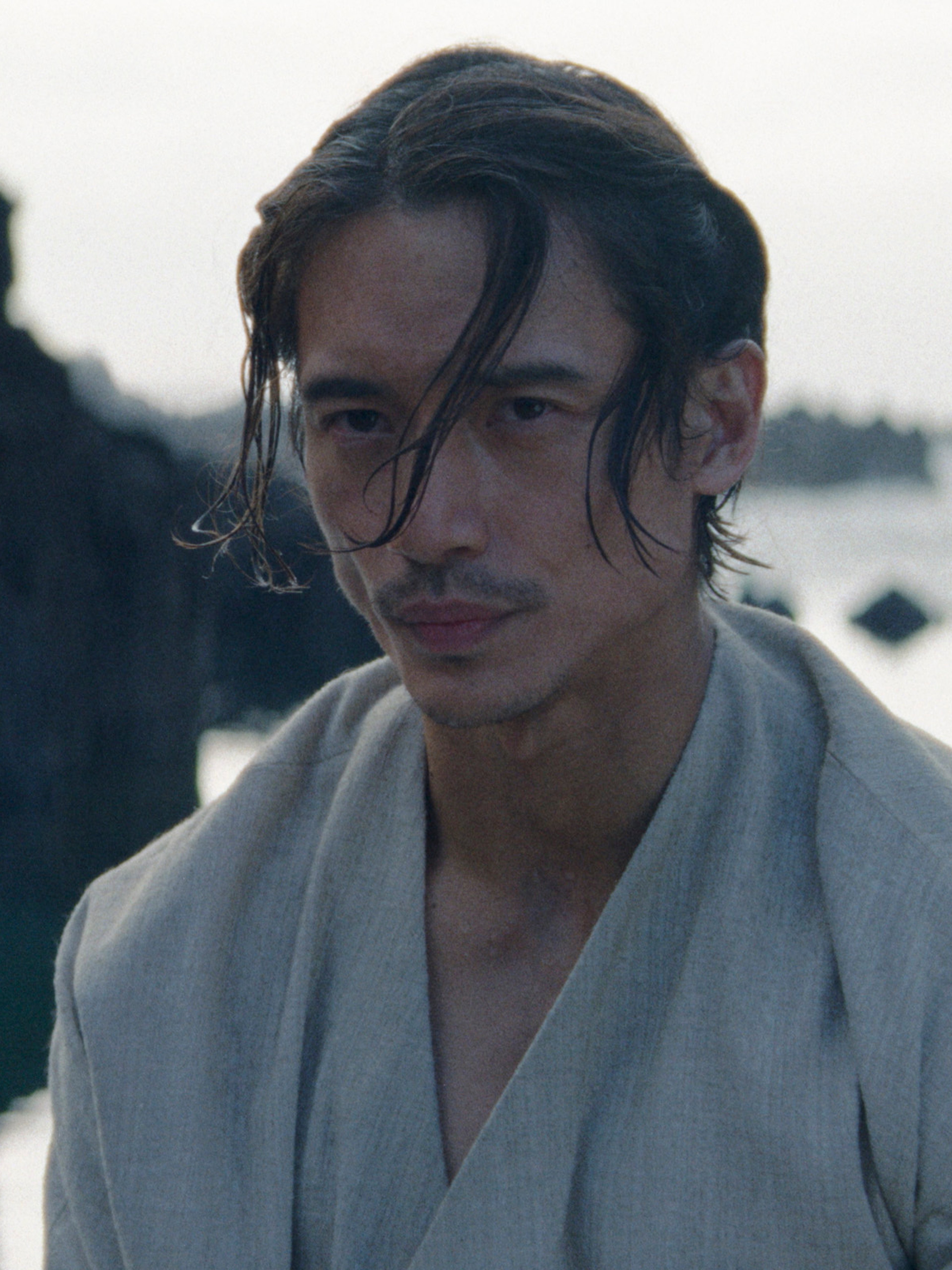 A man with long dark hair wearing a white robe