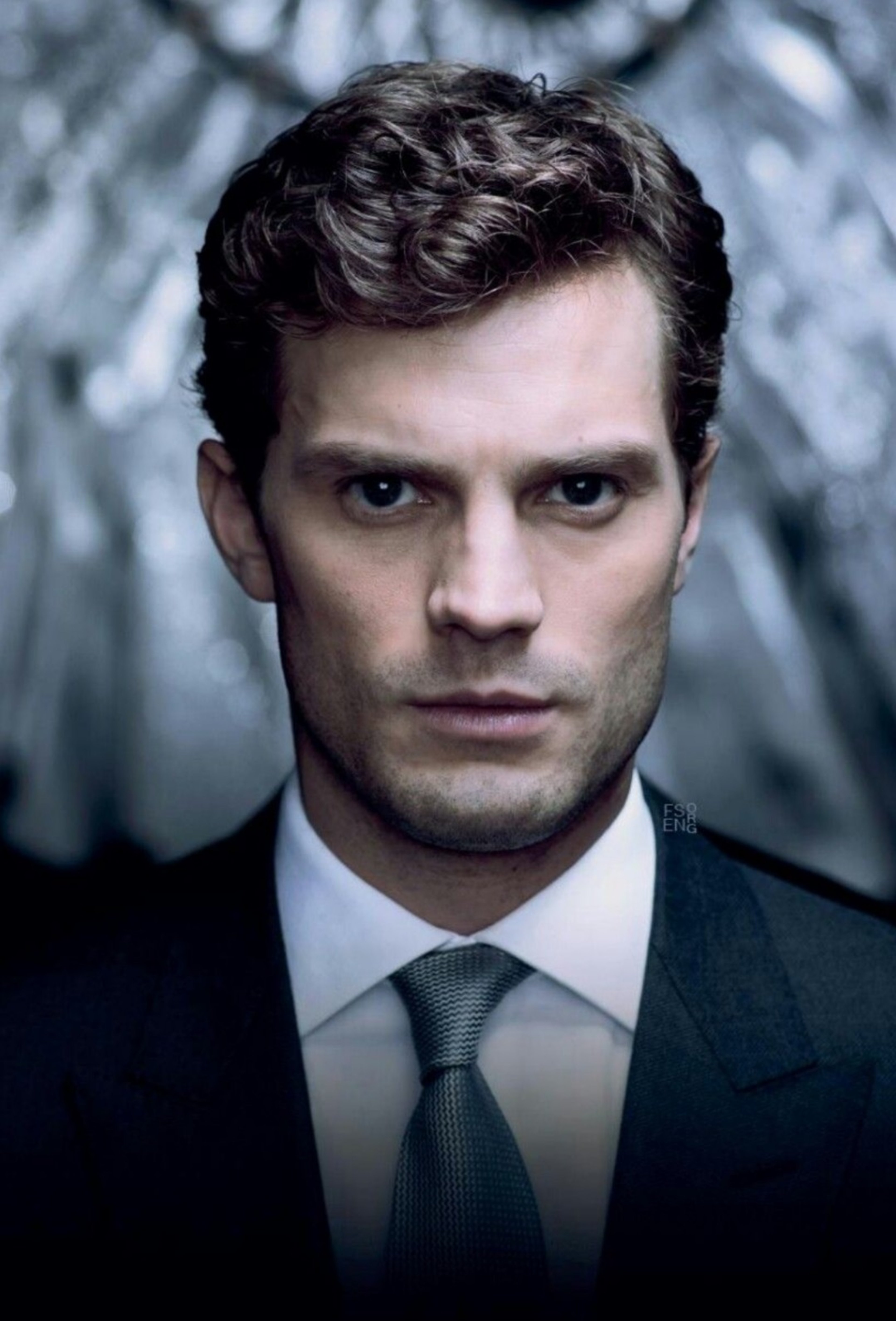 A close-up portrait of a serious-looking young man in a suit and tie