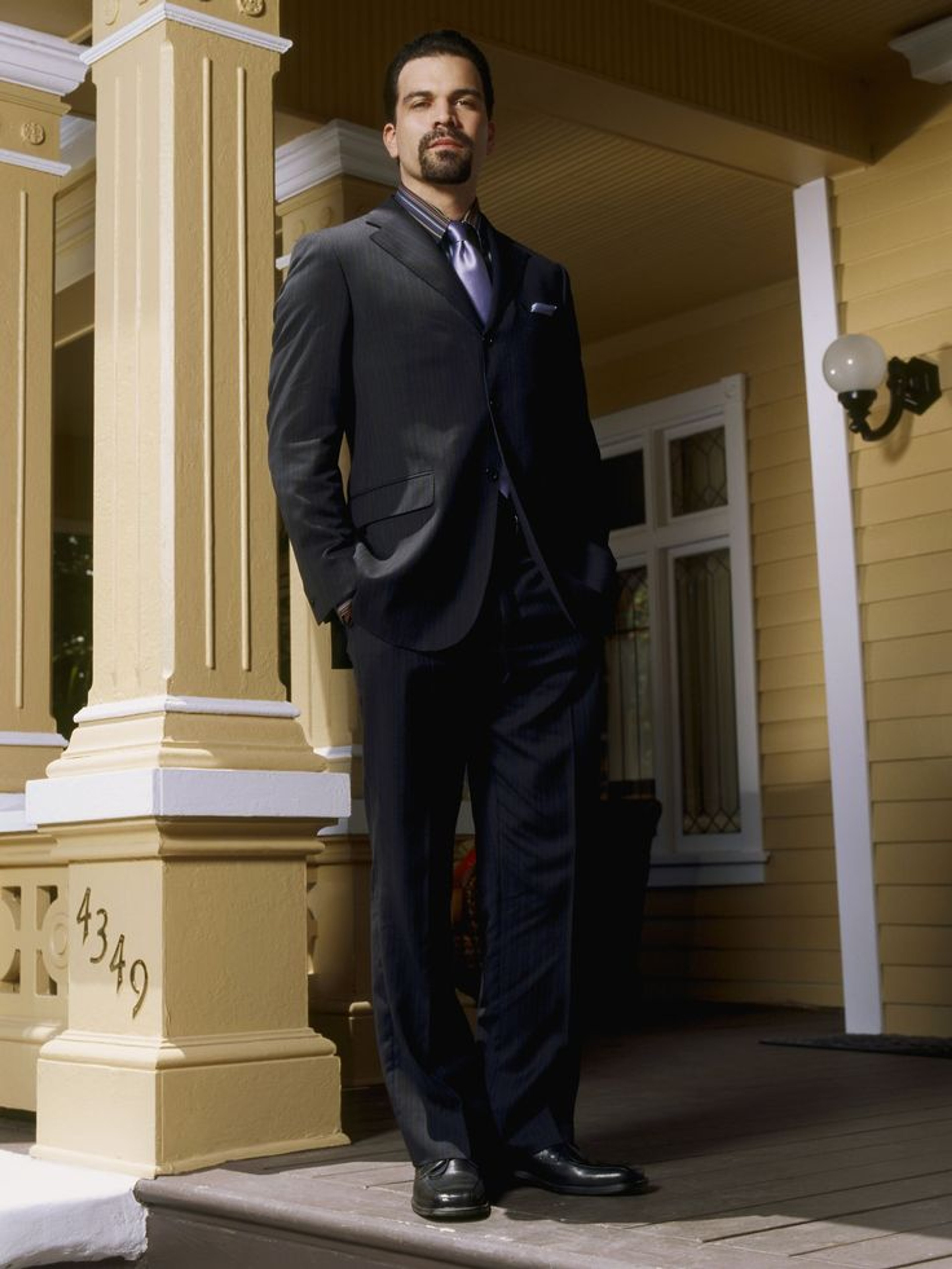 A well-dressed man in a suit standing on the steps of a building