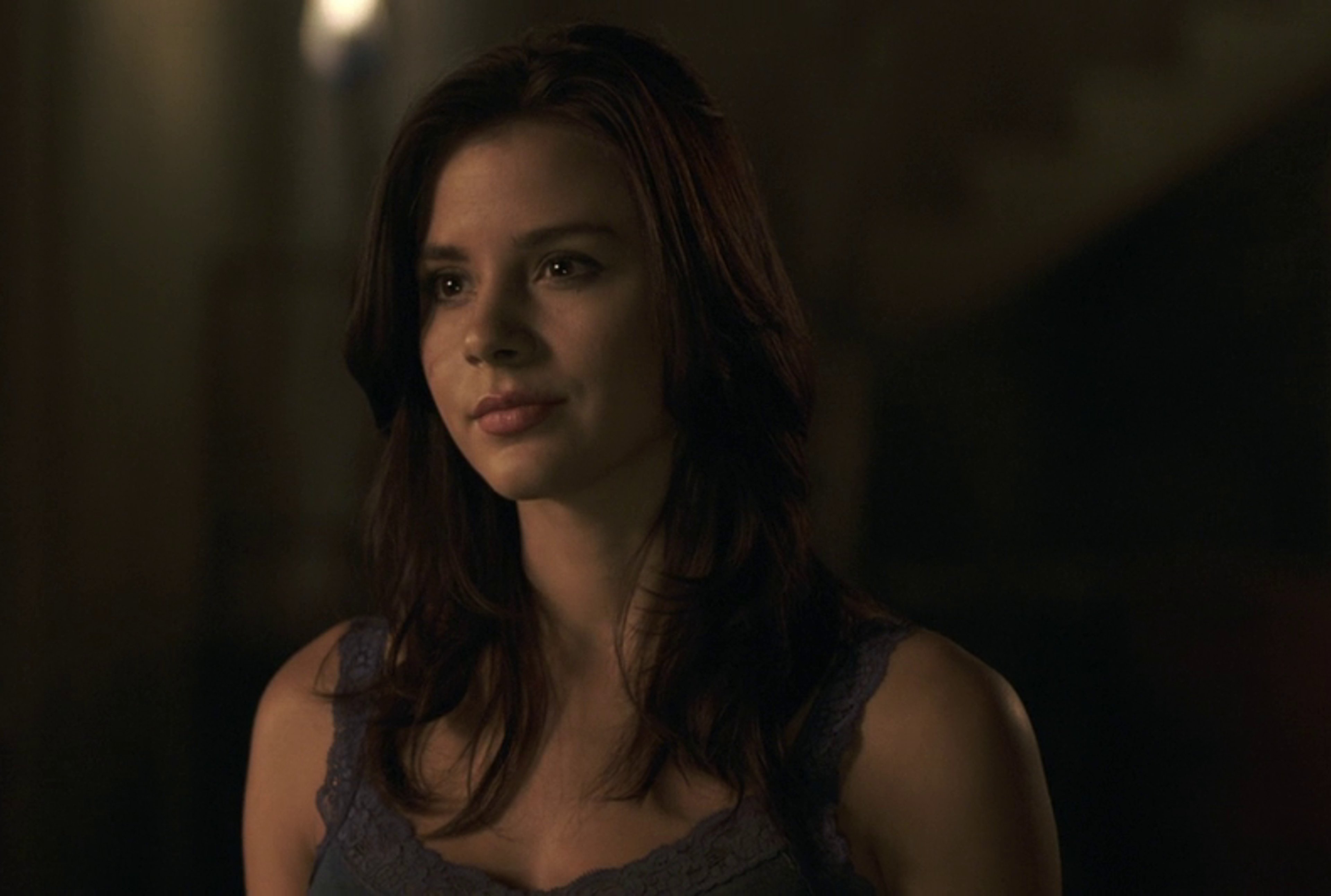 A young woman with long dark hair in a dimly lit setting