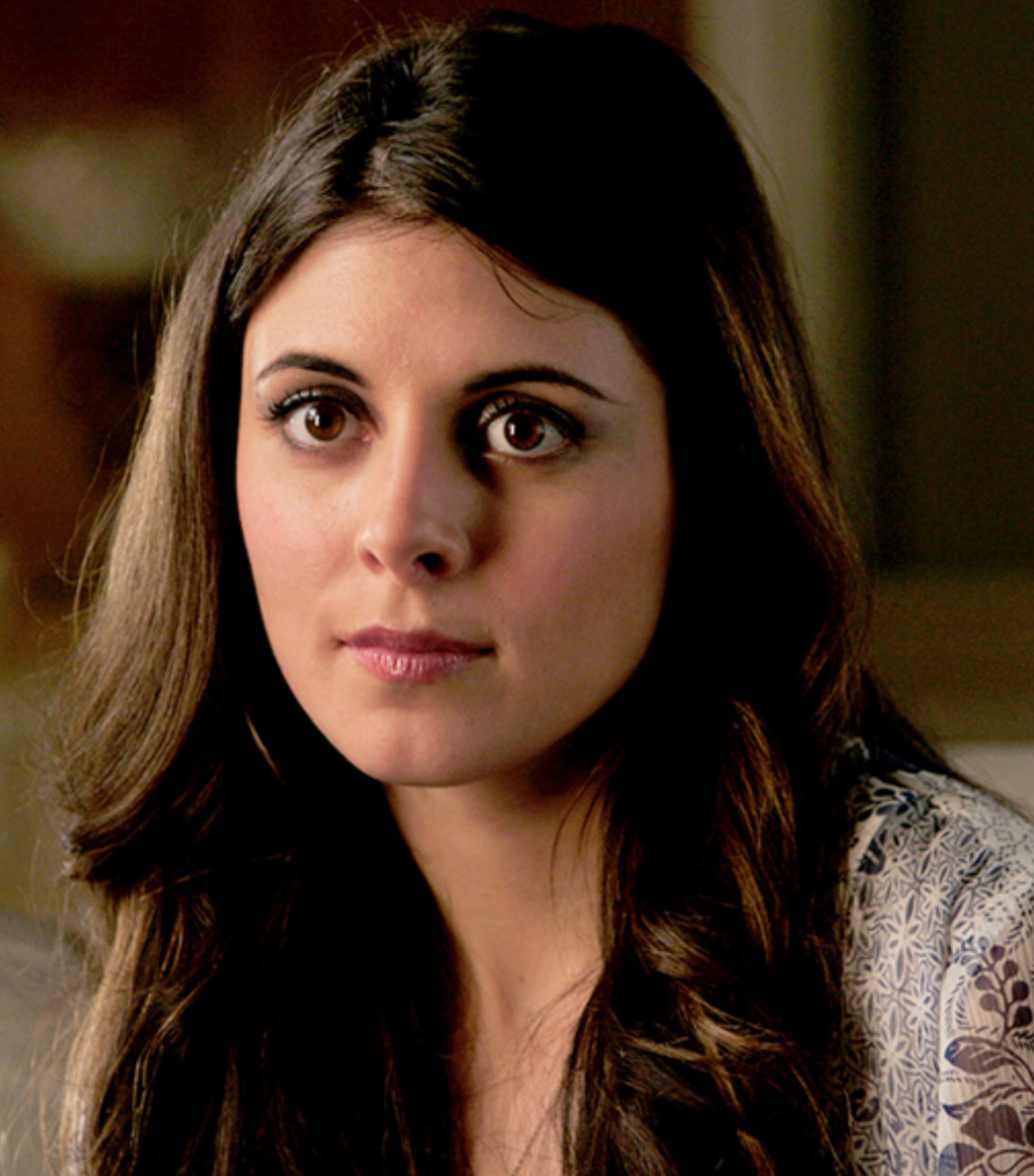 A young woman with dark hair and a serious expression