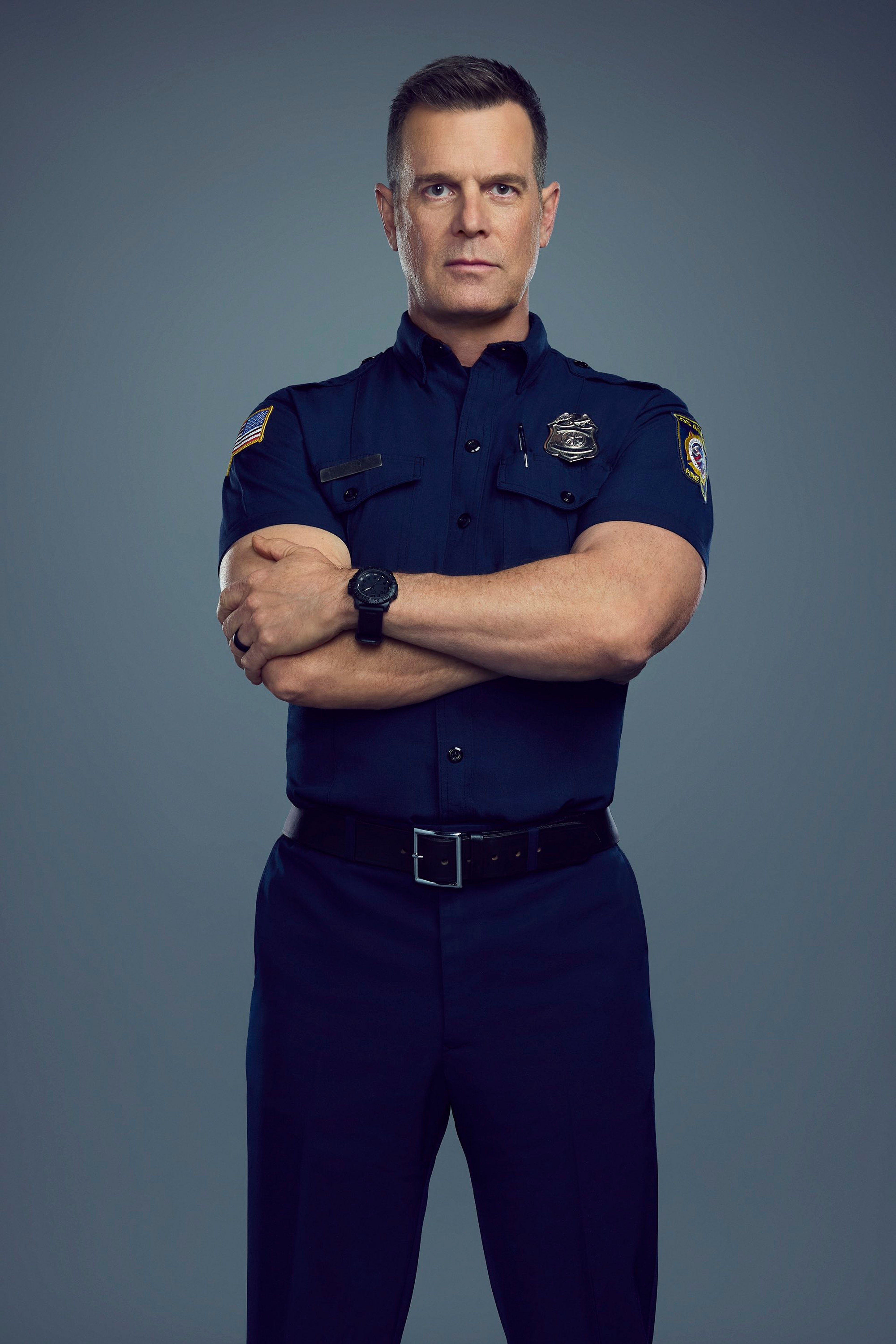 A middle-aged man in a fire department uniform standing with a serious expression