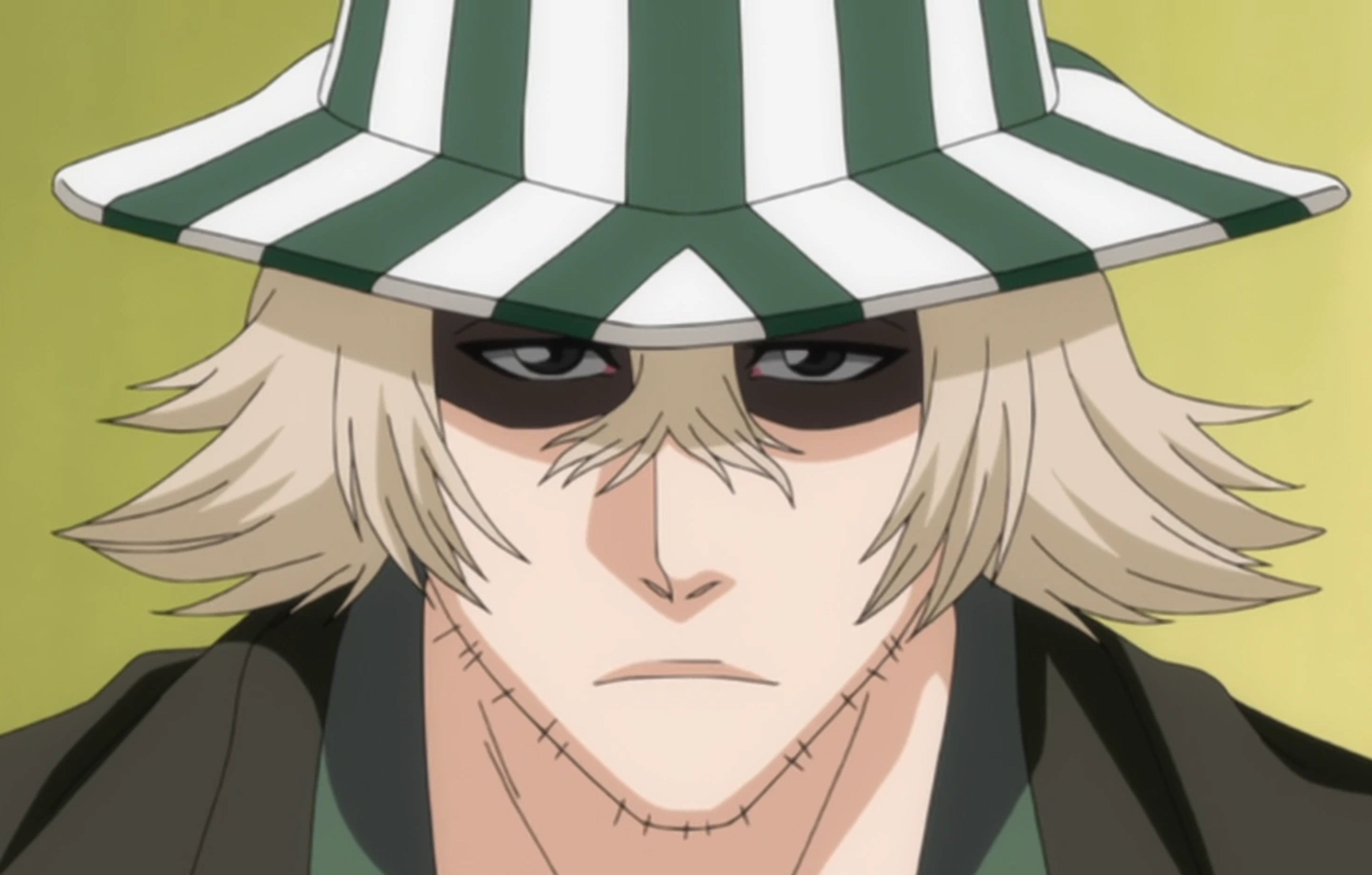 A man with blond hair and a striped hat wearing a green kimono and black coat