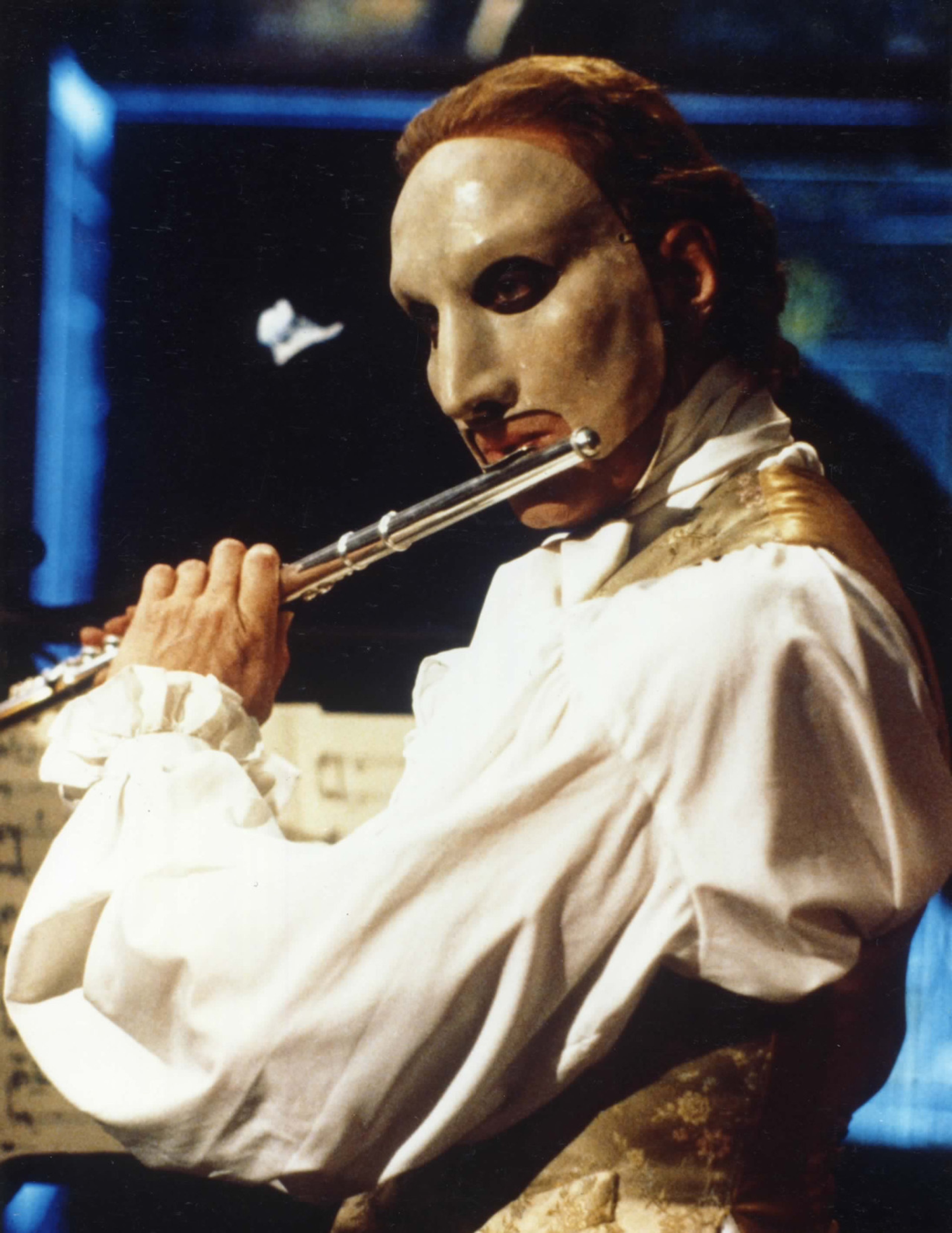 A man with a white mask playing a musical instrument