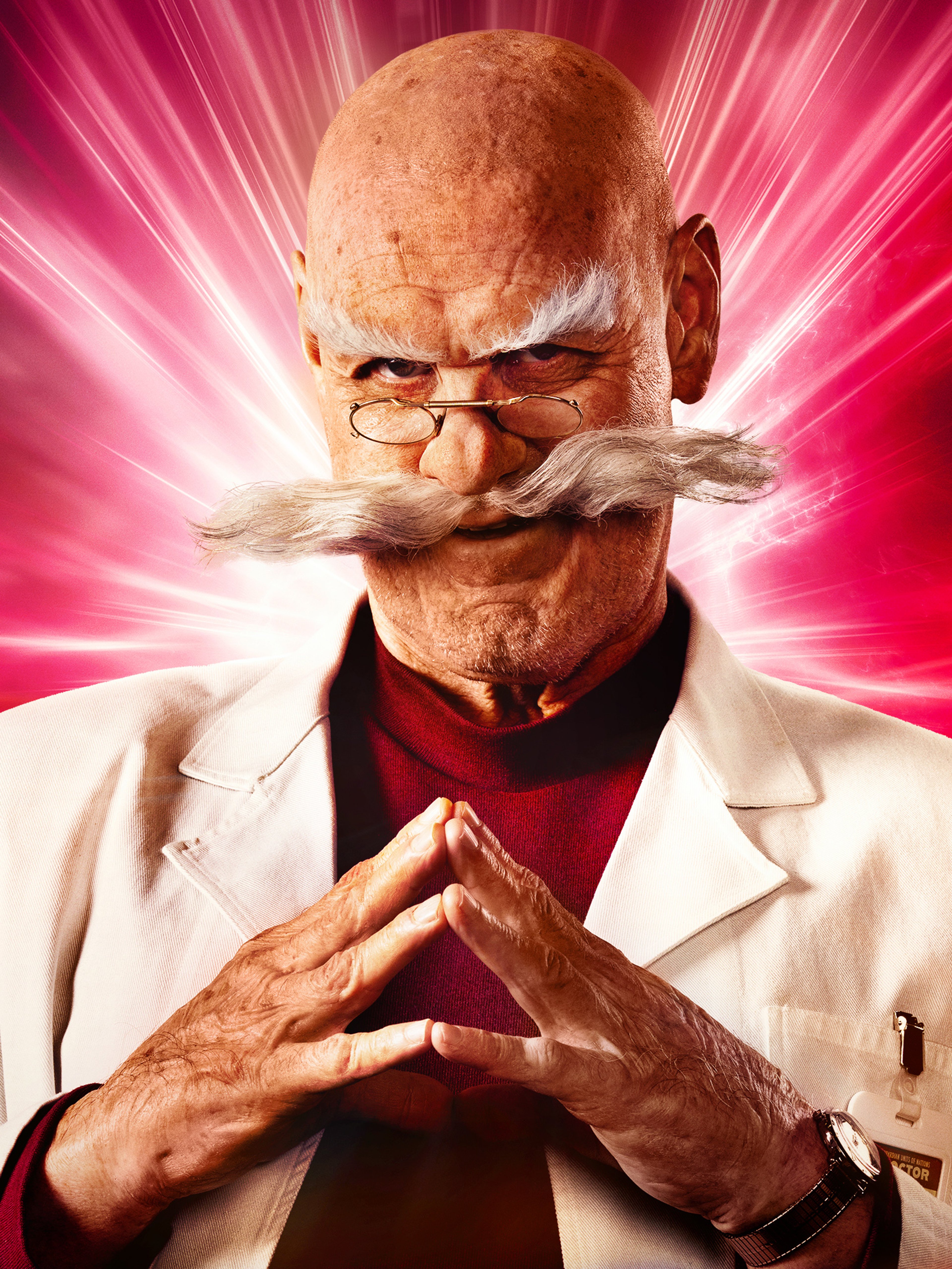 An elderly bald man with a large white mustache wearing a white lab coat, making a praying or pleading gesture against a bright, colorful background.