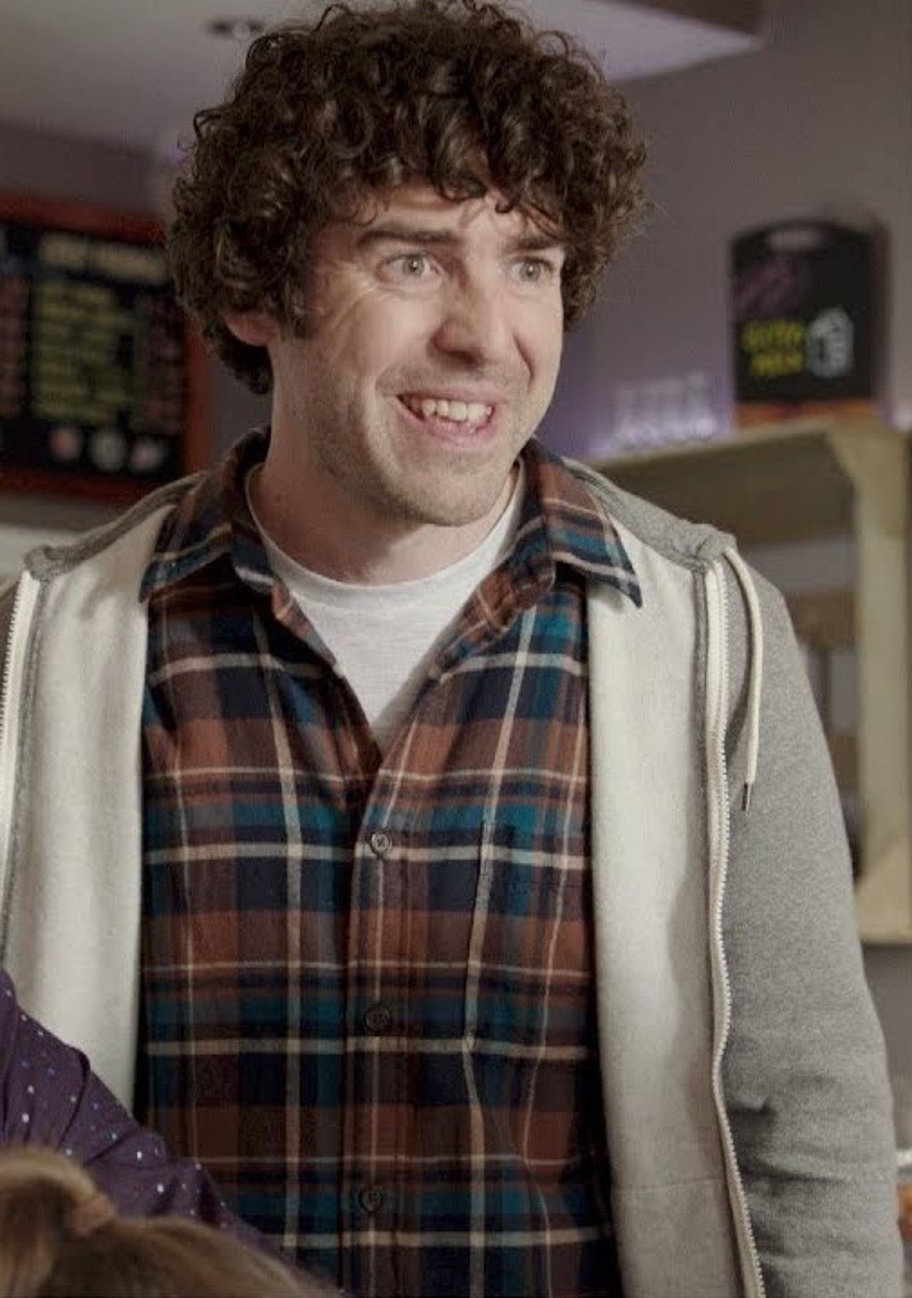 A middle-aged man with curly brown hair and a friendly expression, wearing a plaid shirt and jacket.