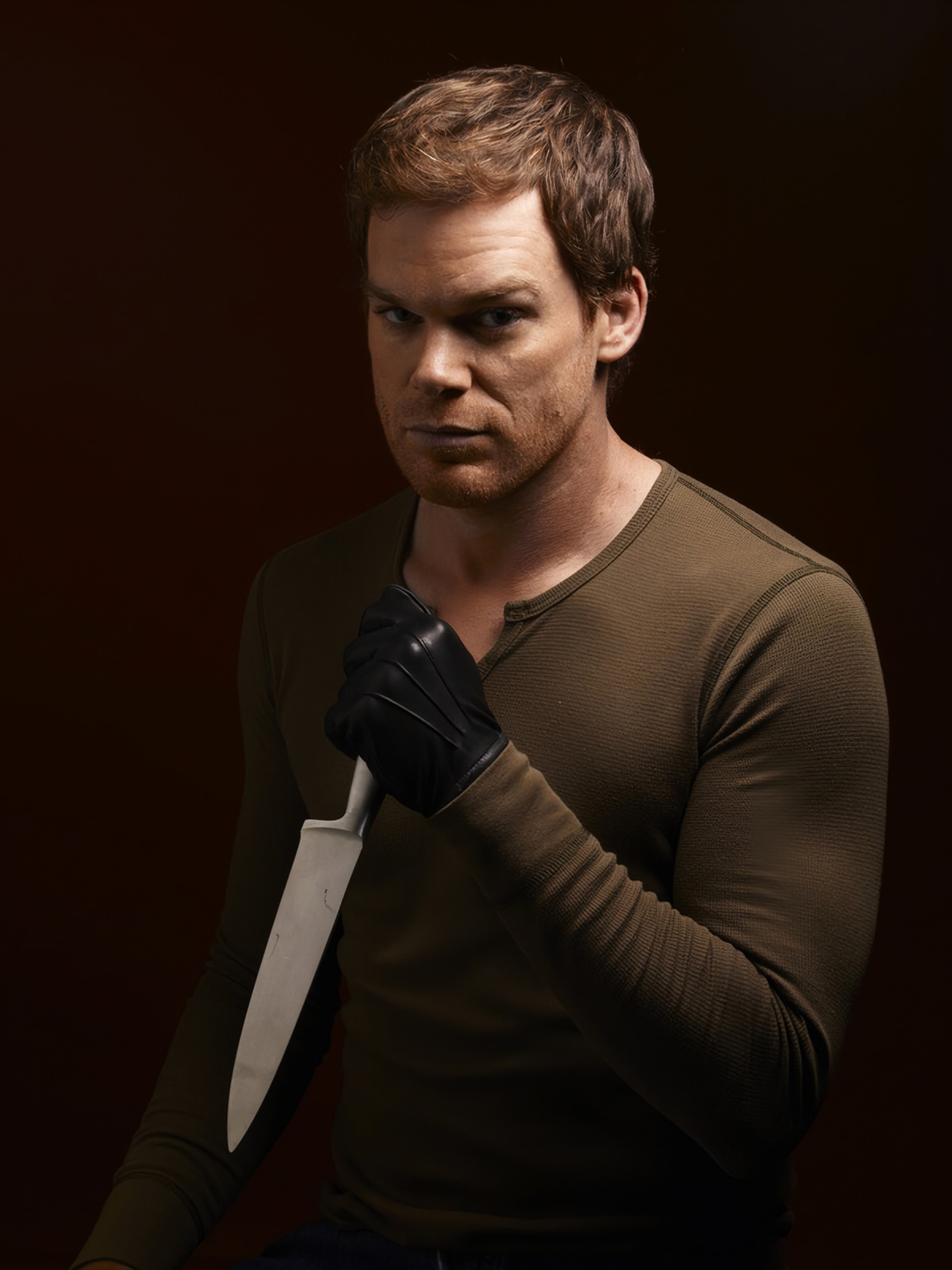 A man with short brown hair wearing a dark green sweater