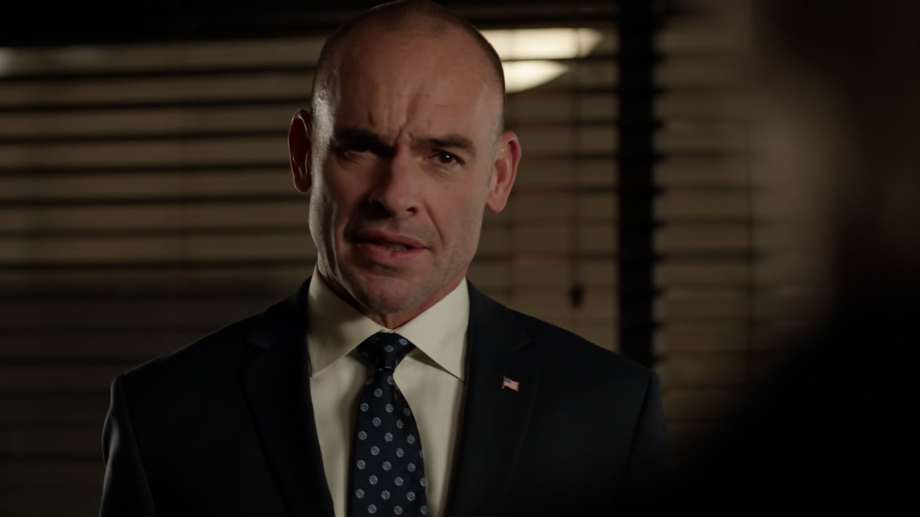 A middle-aged man in a suit and tie with a serious expression