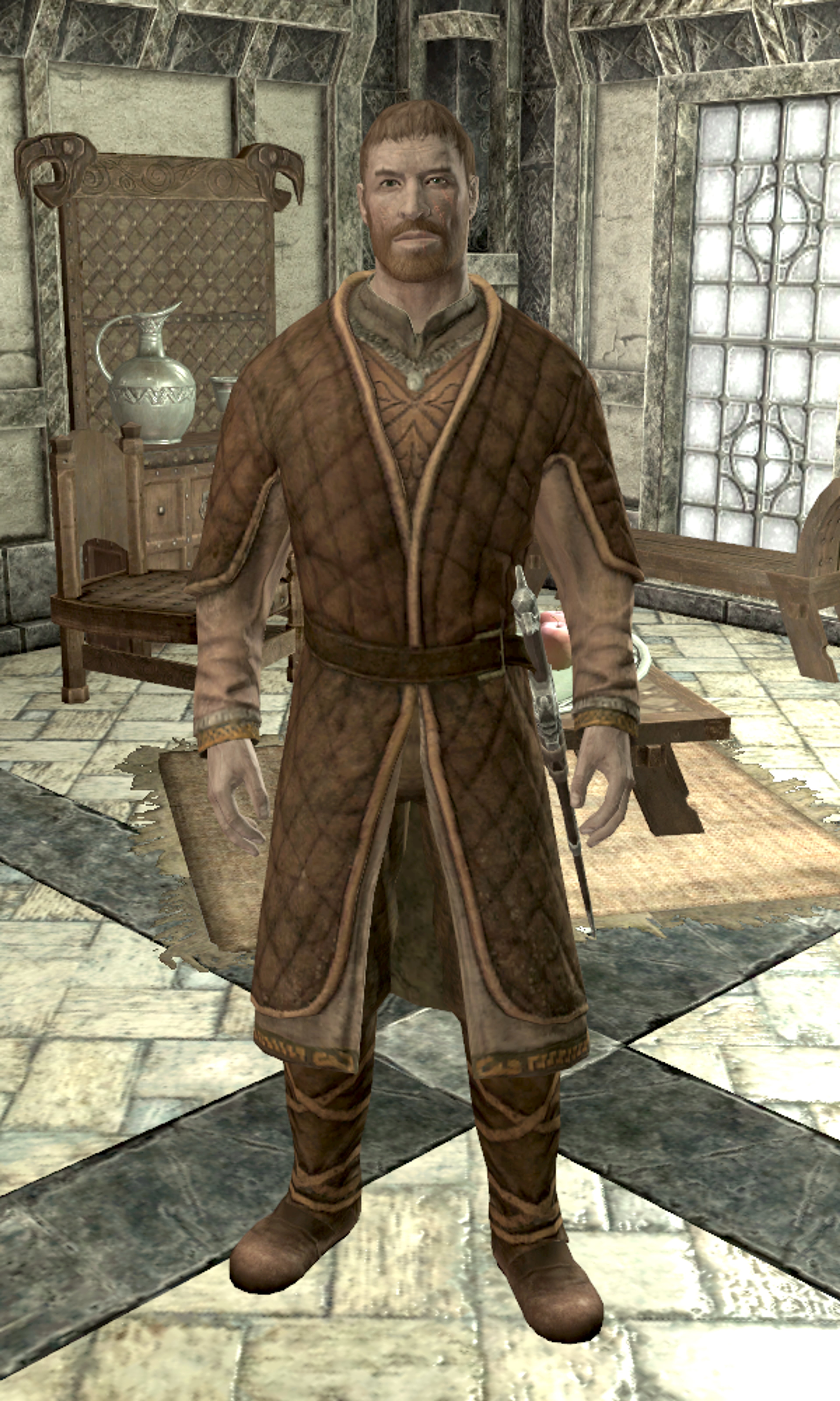 A middle-aged Nord man with a red beard wearing a brown and tan plaid robe or coat, standing in a room with wooden furniture.