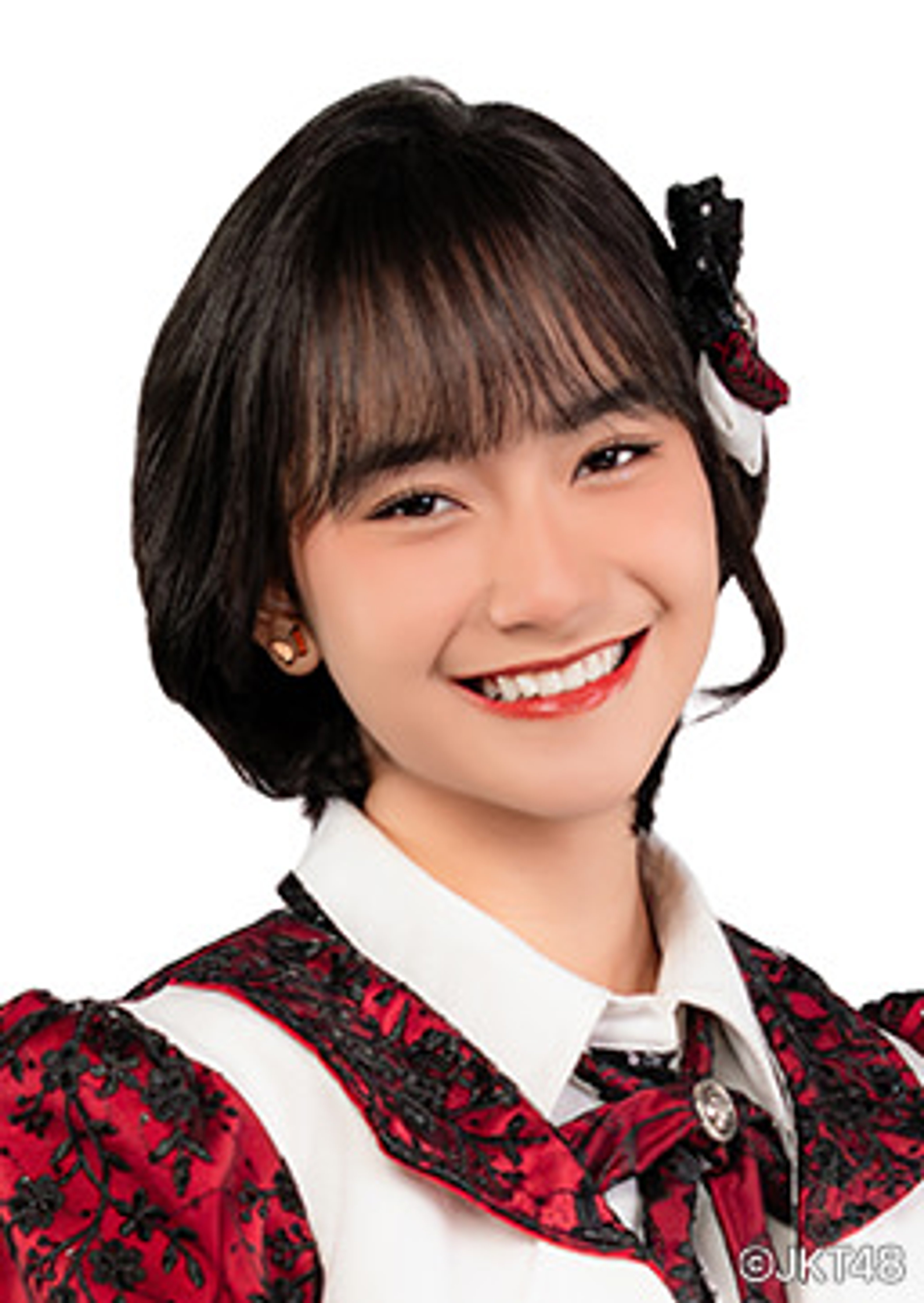 A smiling young woman with short dark hair wearing a red and black patterned dress