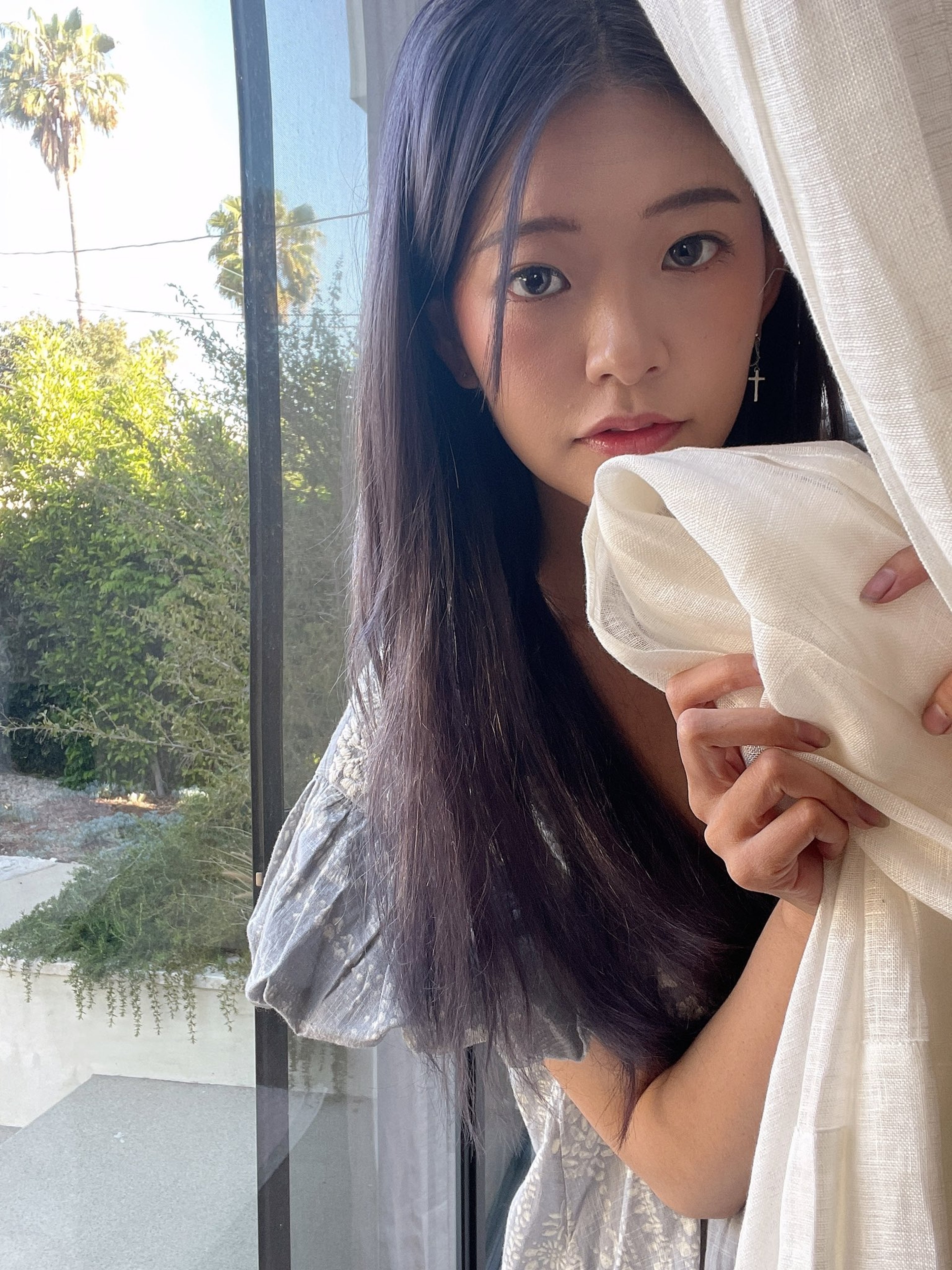 A young Asian woman with long dark hair looking out a window