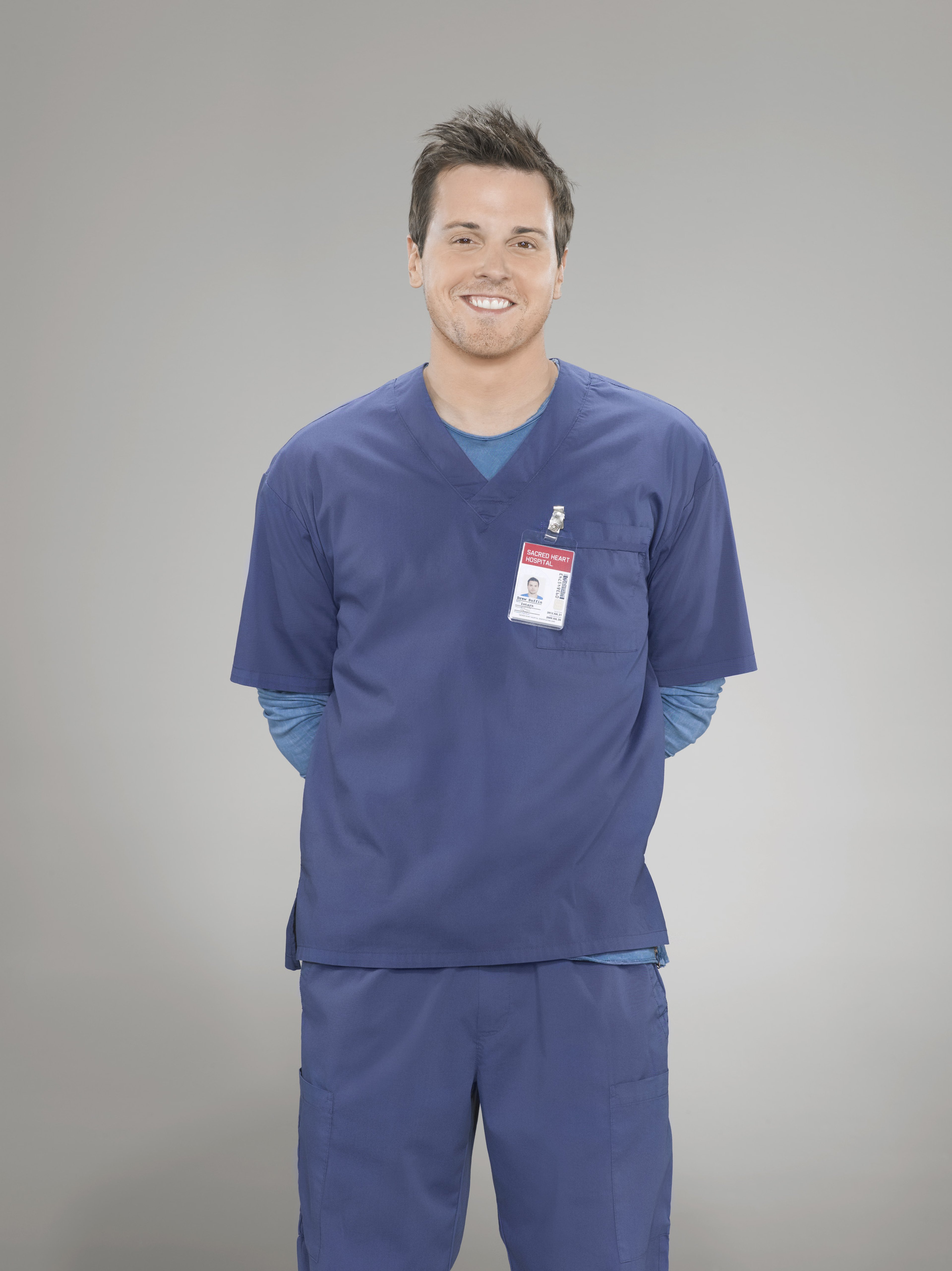 A man in medical scrubs with a name tag