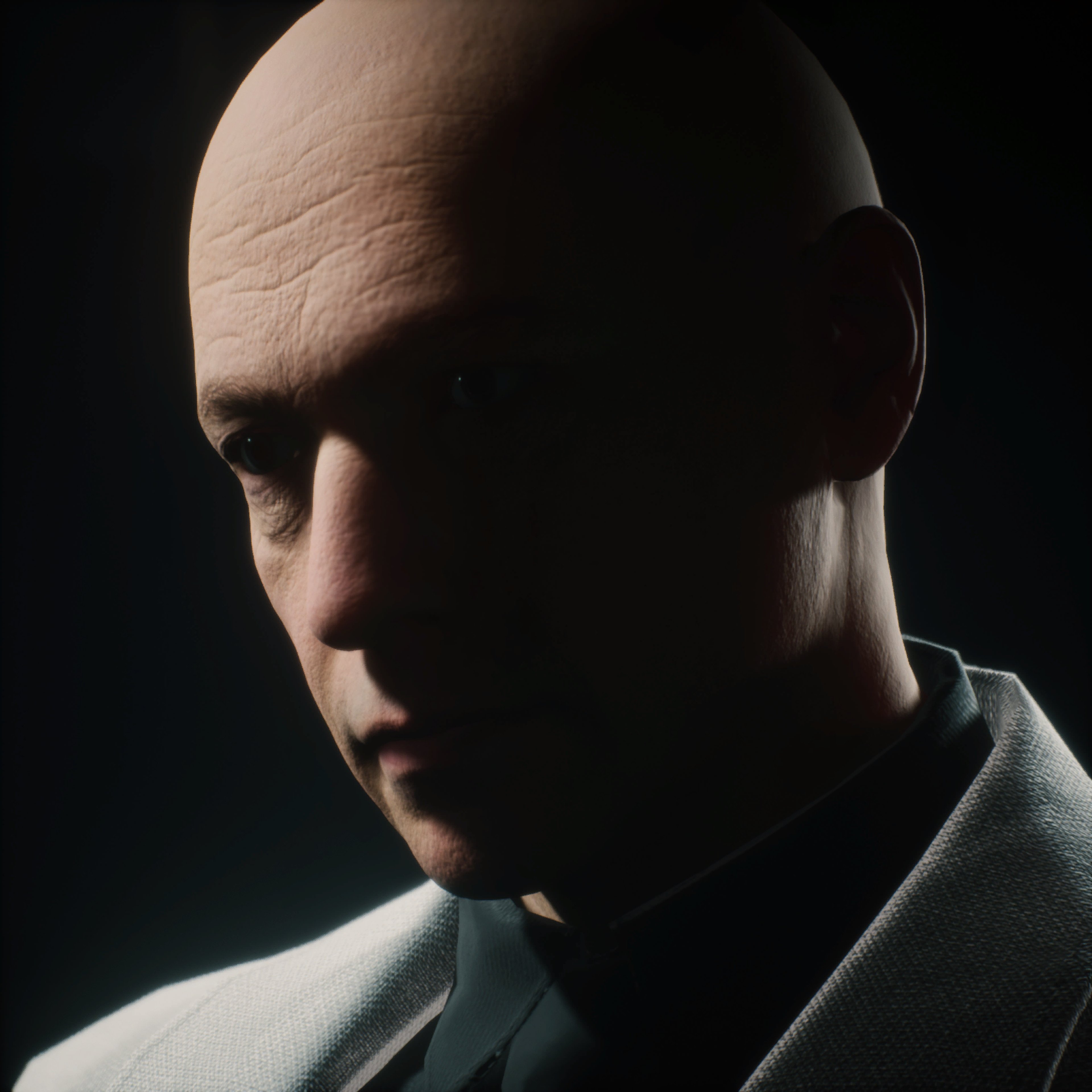 A close-up portrait of a bald, middle-aged man with a stern expression, wearing a dark suit or jacket.