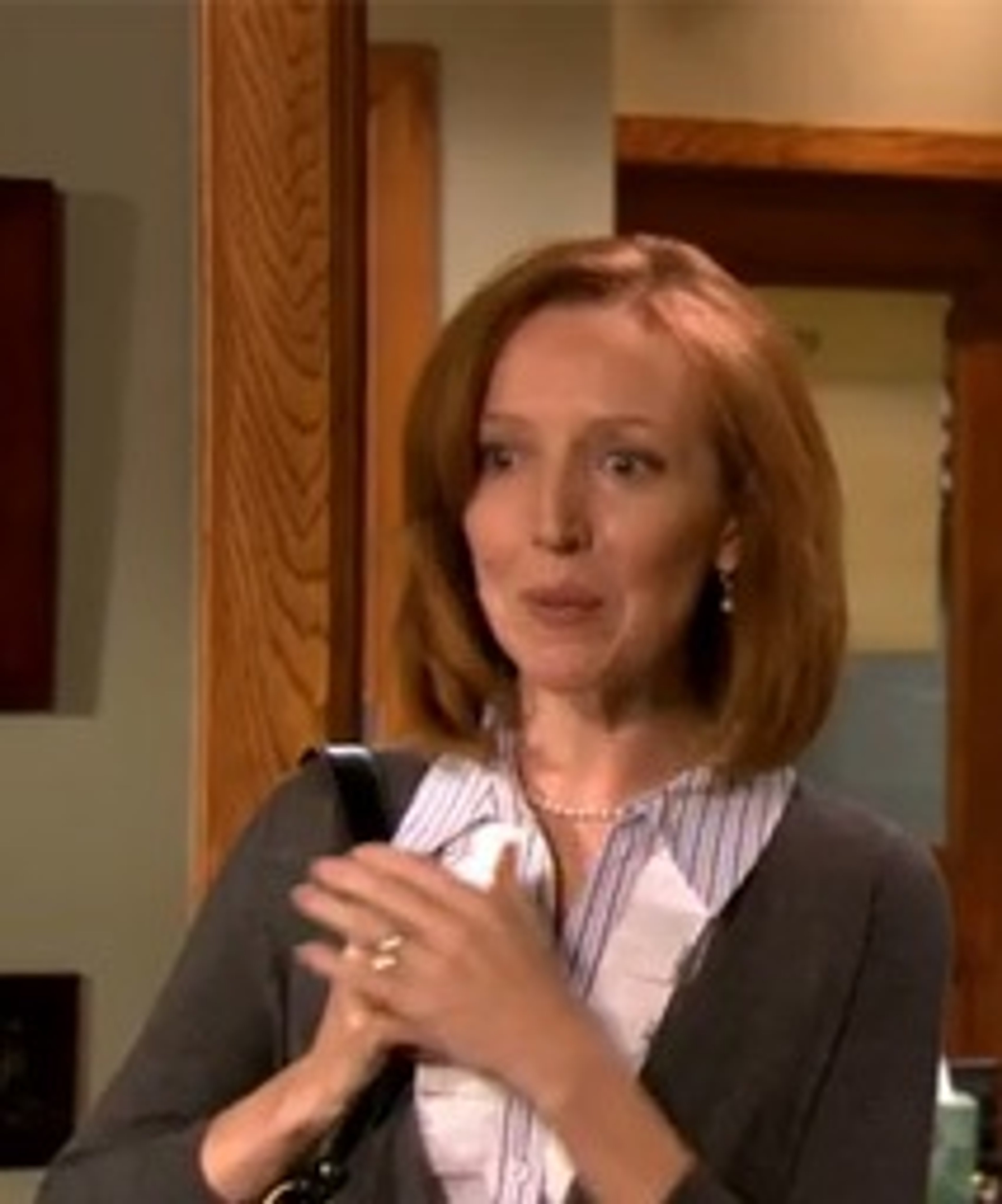 A middle-aged woman with short, reddish-brown hair wearing a pink blouse and black blazer.