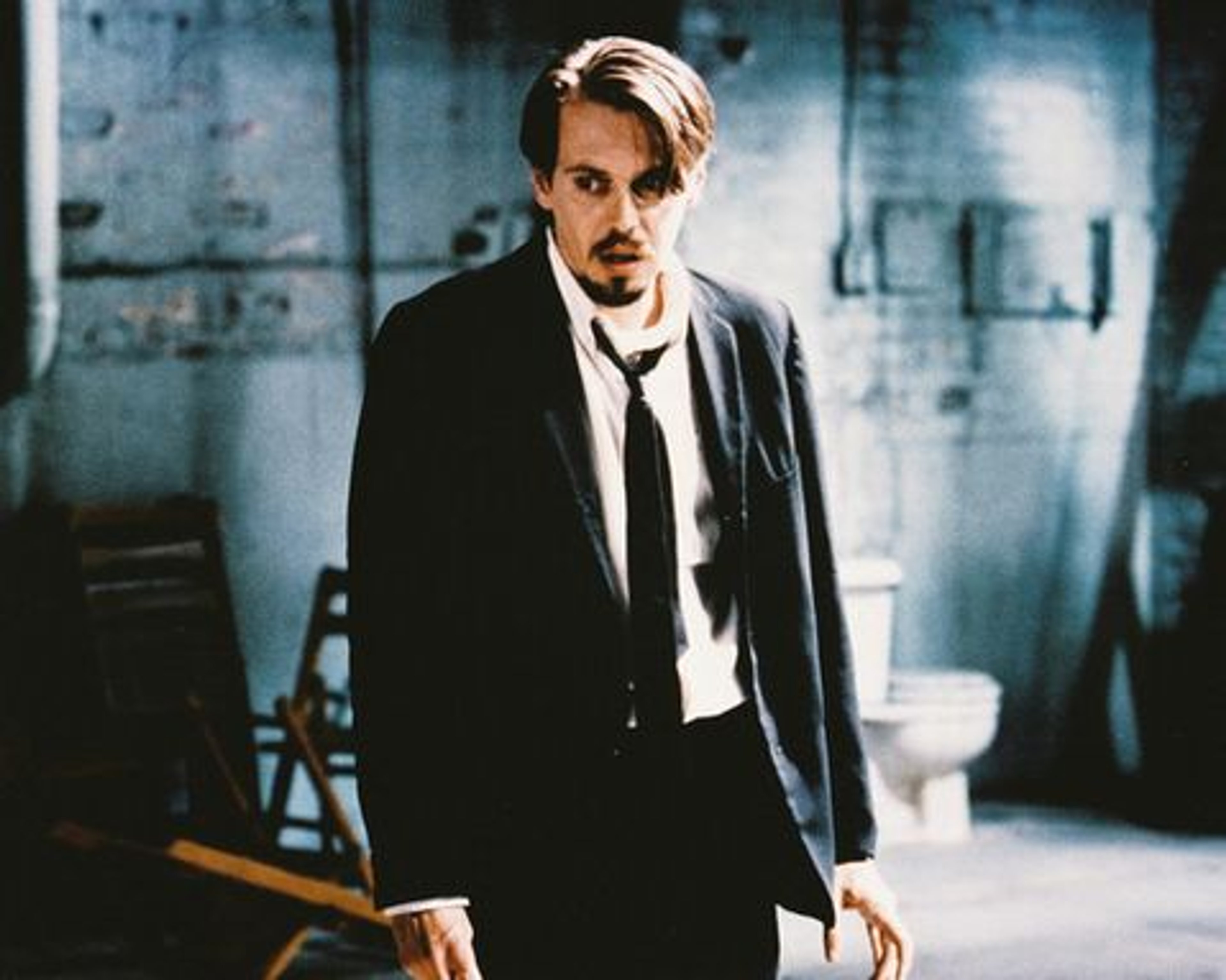 A man in a black suit standing in a dimly lit room
