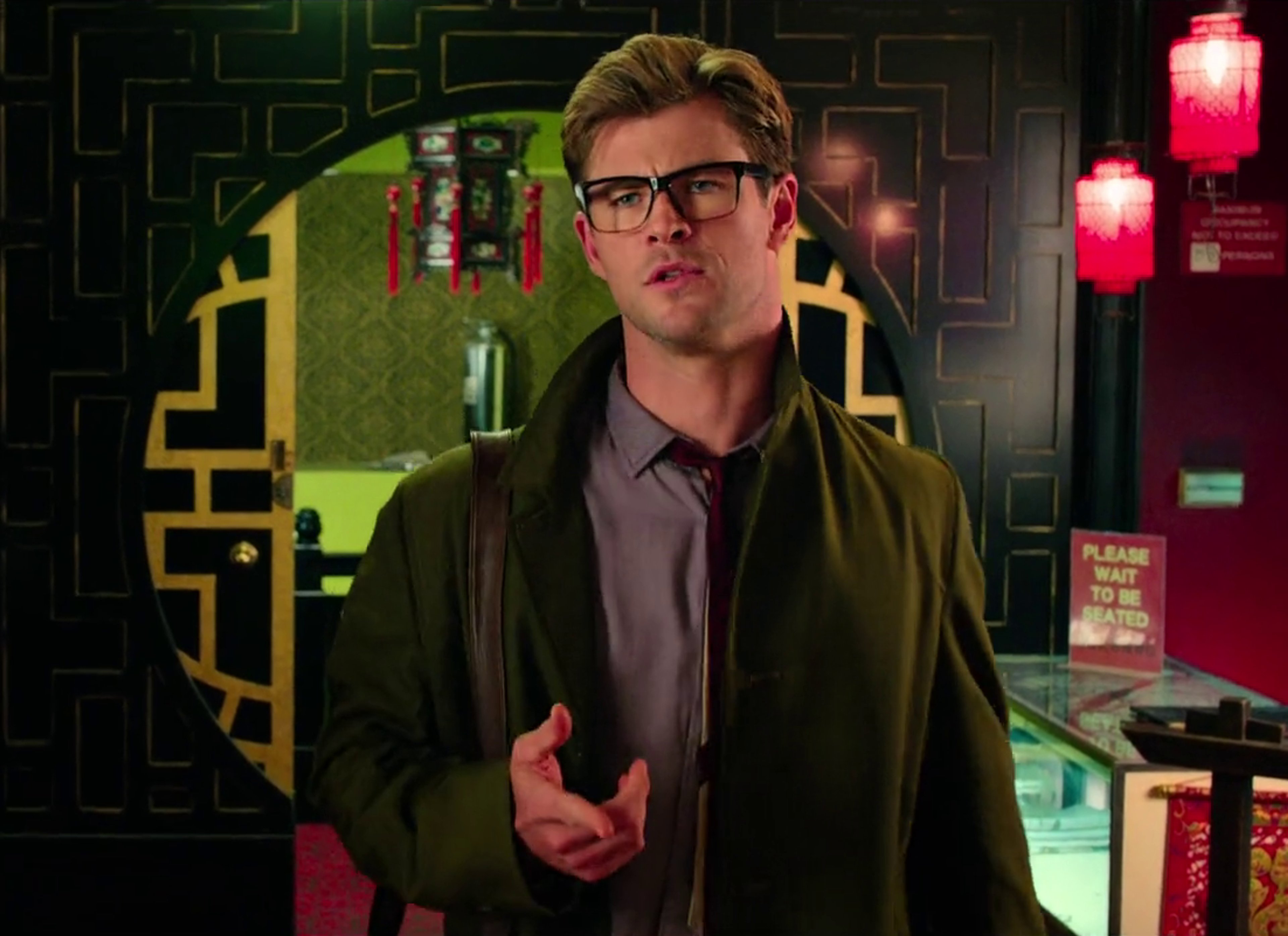 A man with short brown hair and glasses wearing a green jacket