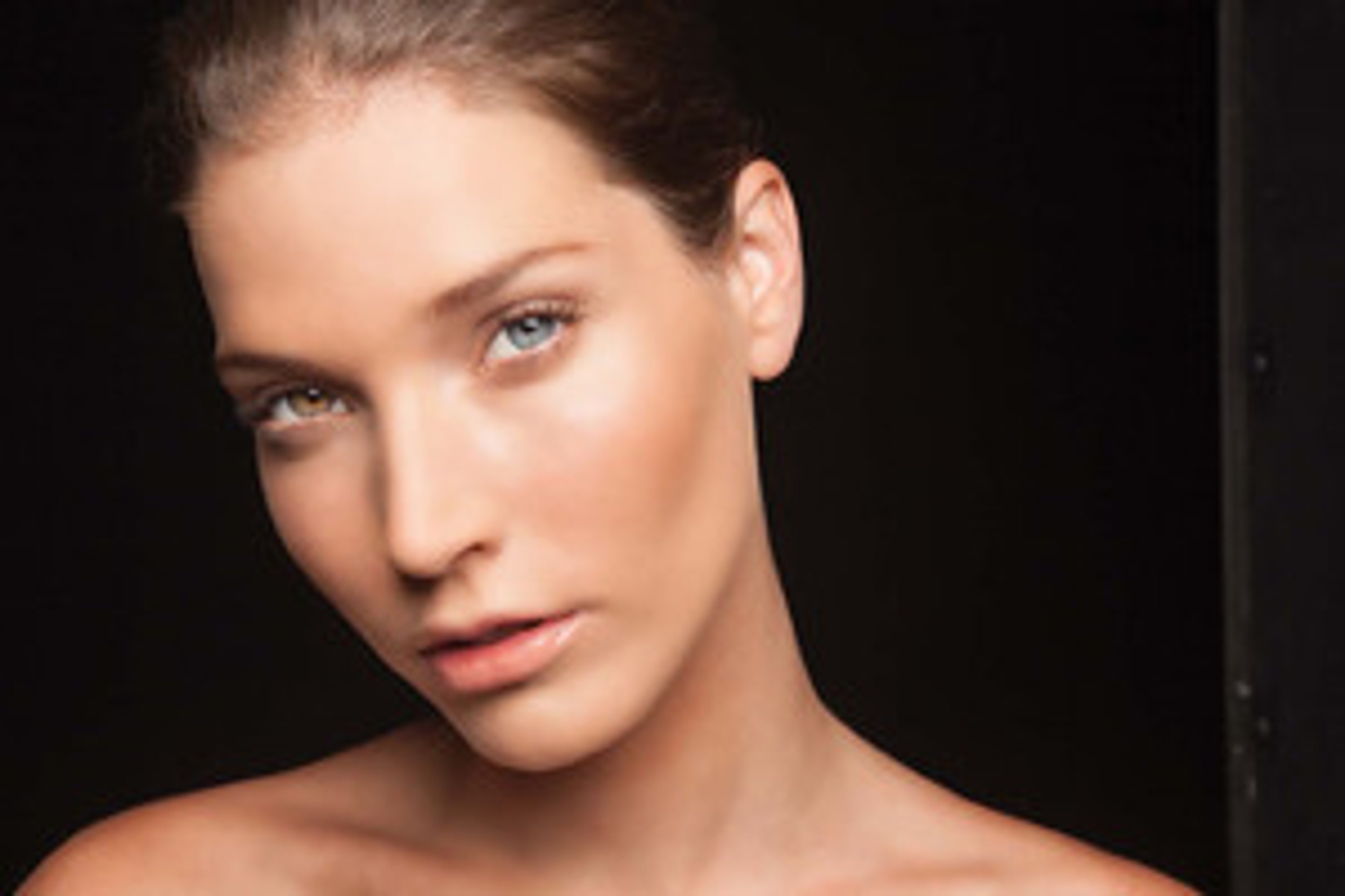 Close-up portrait of a woman with piercing blue eyes and dark hair
