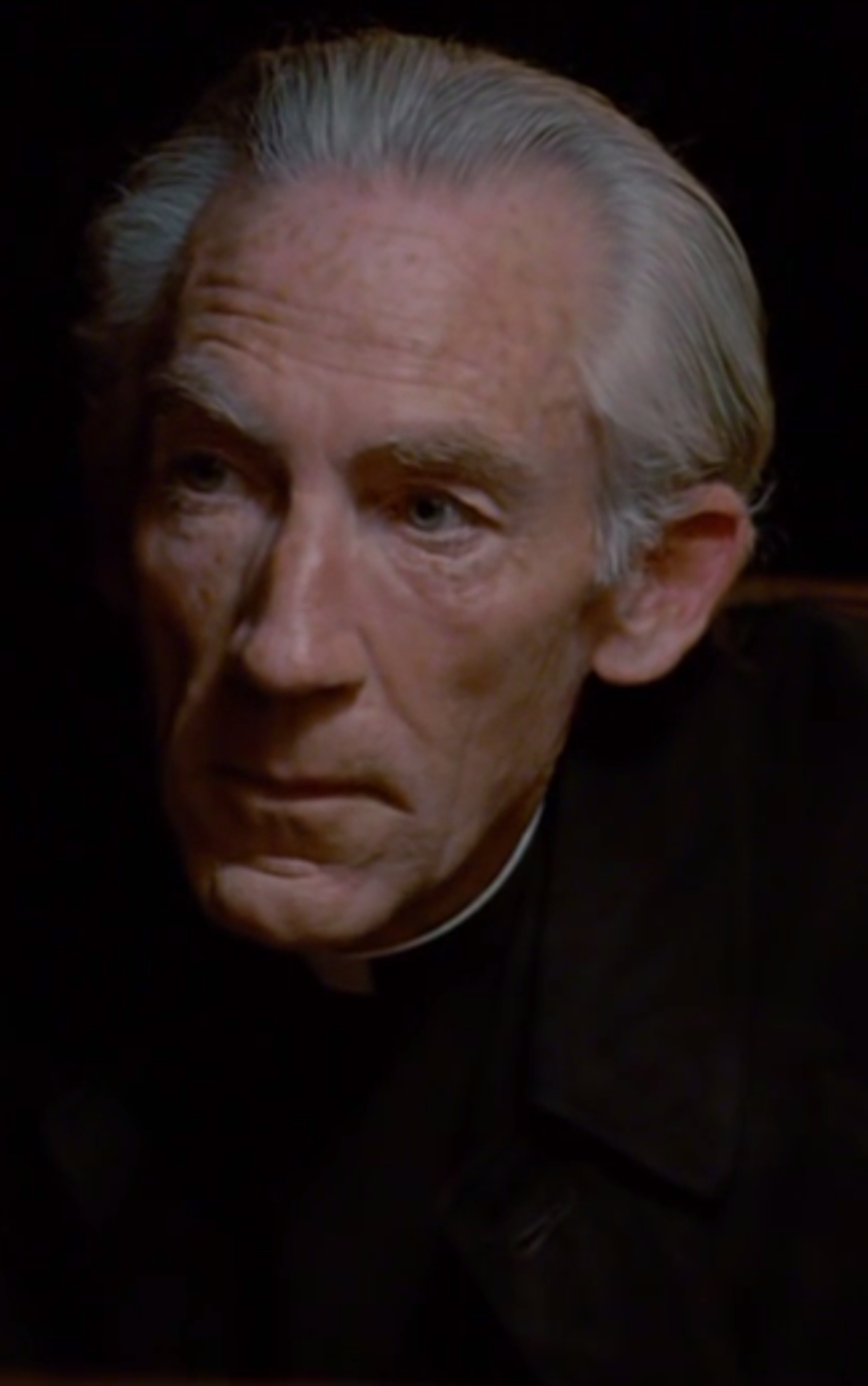 An elderly Catholic priest with white hair and blue eyes