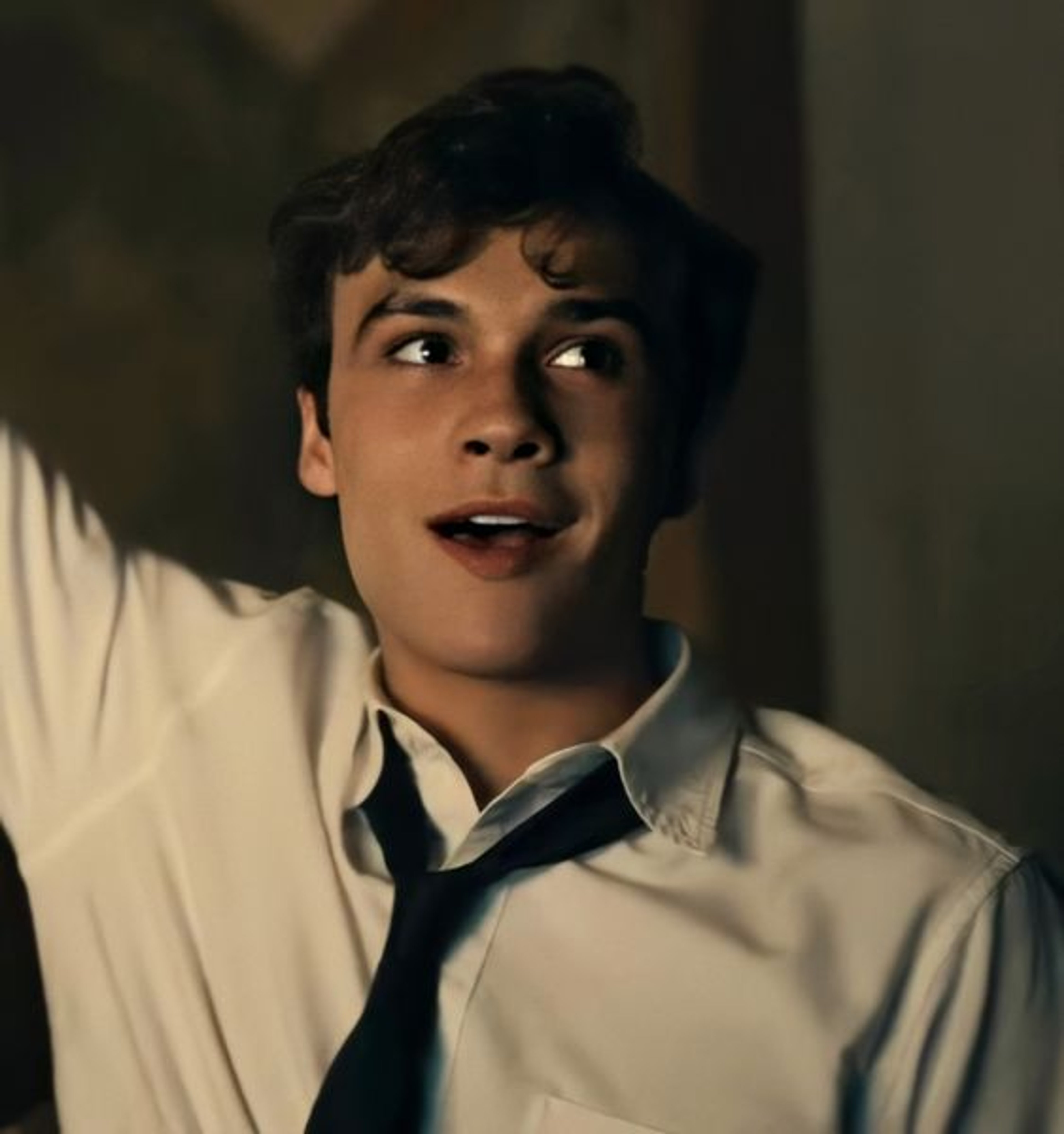 A young man in a white shirt and tie with a serious expression