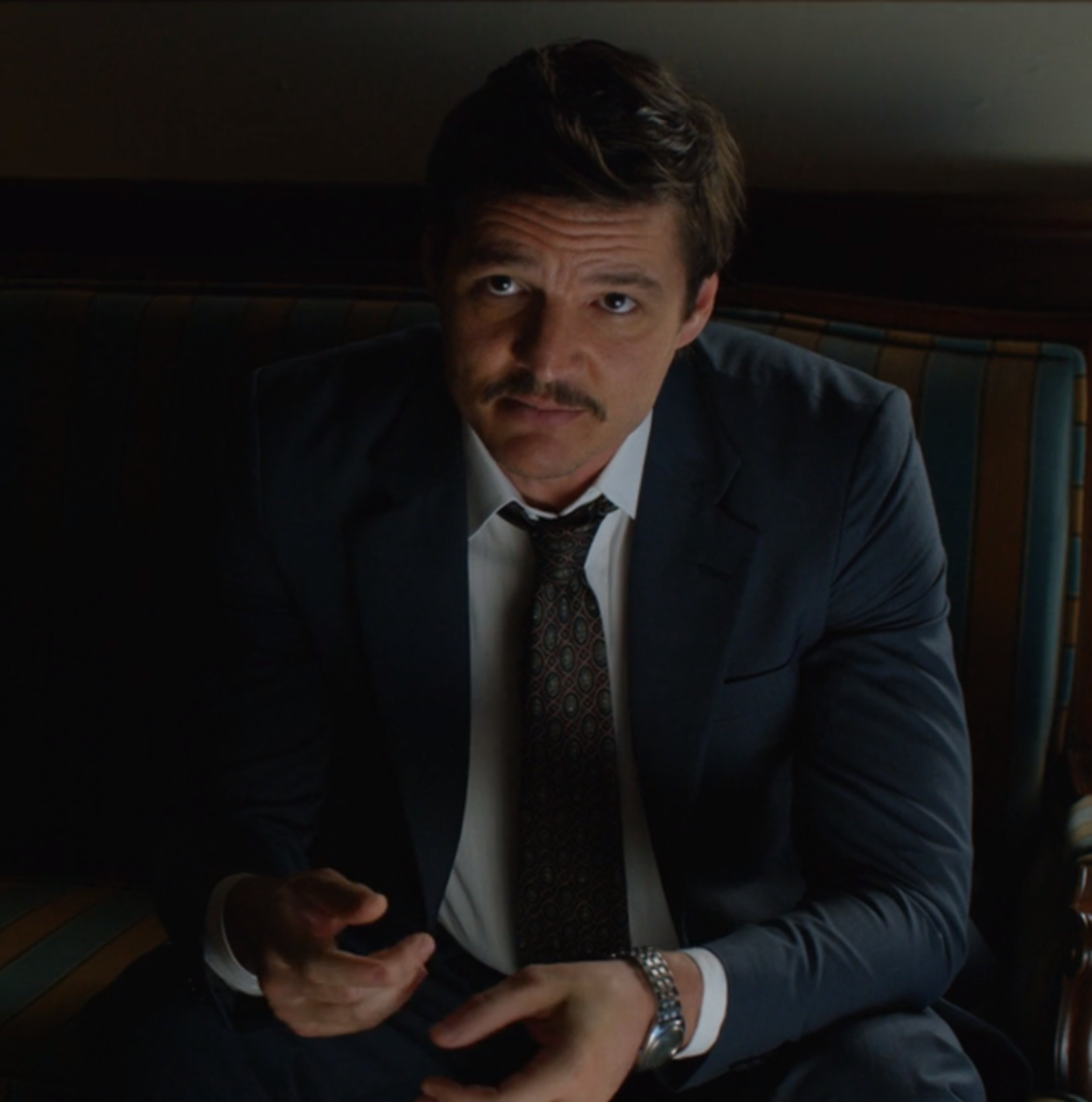 A serious-looking middle-aged man in a suit holding a mobile phone