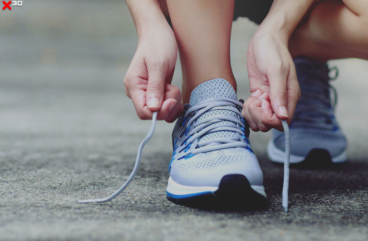Person bindet Schuh und macht sich bereit für ein Outdoortraining