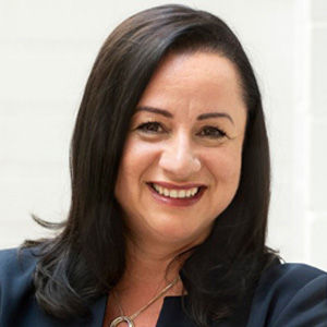 Headshot of Maria Ferraro, a midle-aged woman in a blazer on a light beige background. 