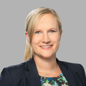 Headshot of Prof. Dr. Claudia Doblinger, a middle aged woman smiling on a simple gray background.